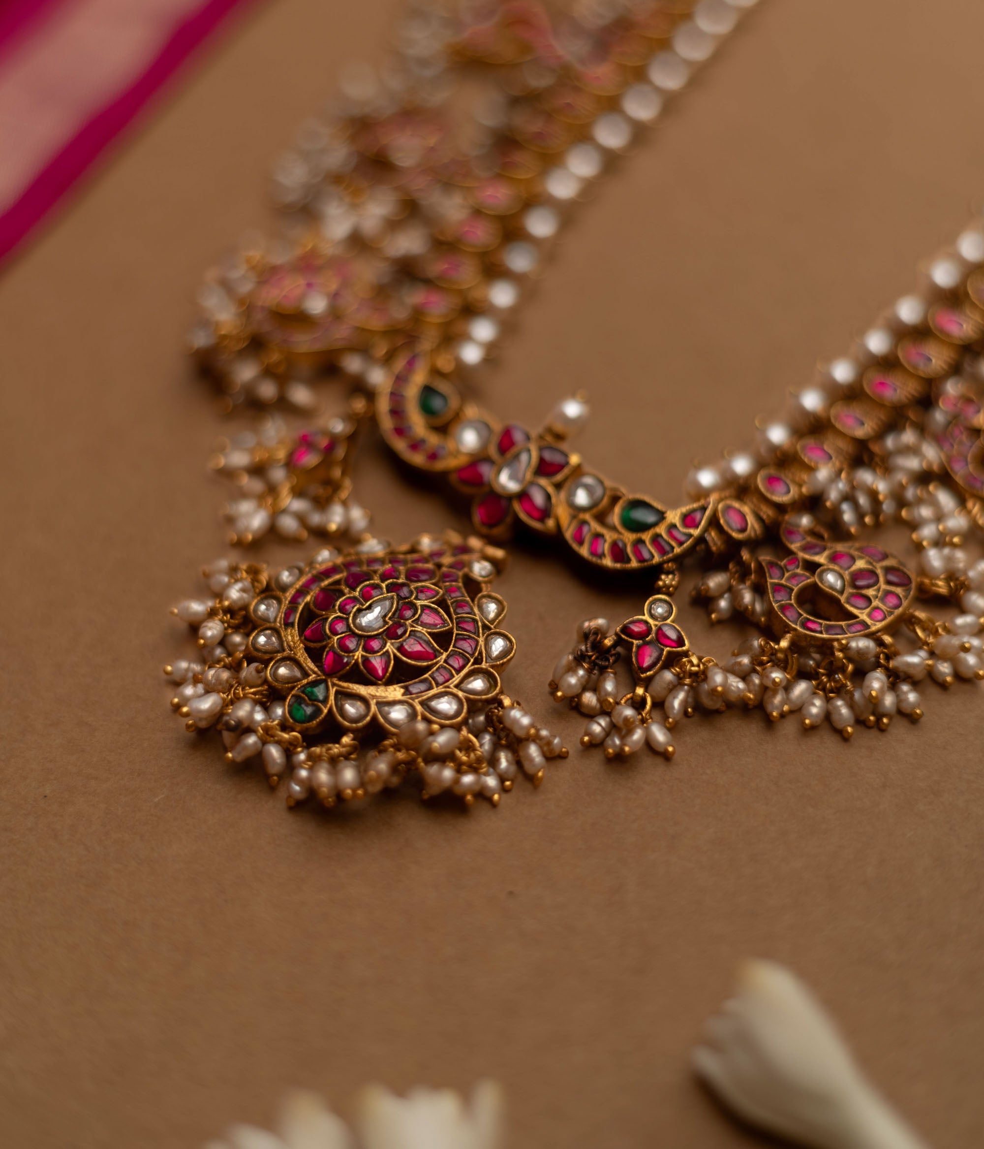 Grand temple-inspired Kundan necklace with shimmering stones, vibrant ruby and emerald accents, and delicate pearl clusters, perfect for weddings and divine celebrations.