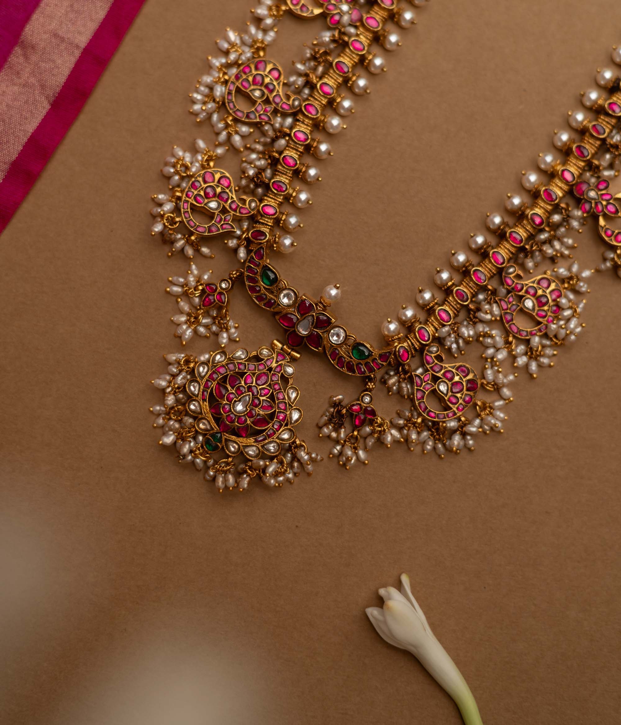 Grand temple-inspired Kundan necklace with shimmering stones, vibrant ruby and emerald accents, and delicate pearl clusters, perfect for weddings and divine celebrations.