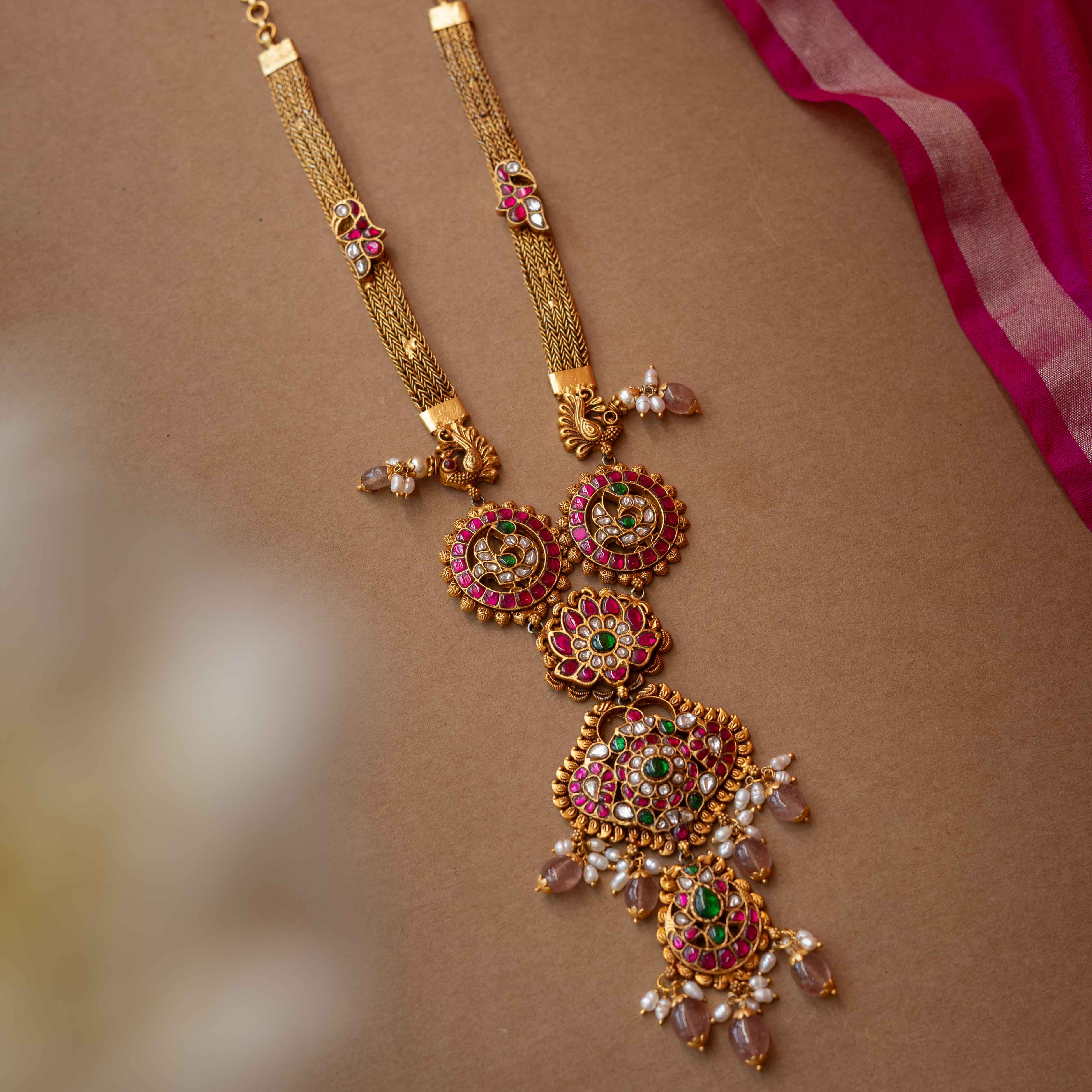 A multi-layered Kundan necklace with a central pendant and cascading strands of pearls and beads.
