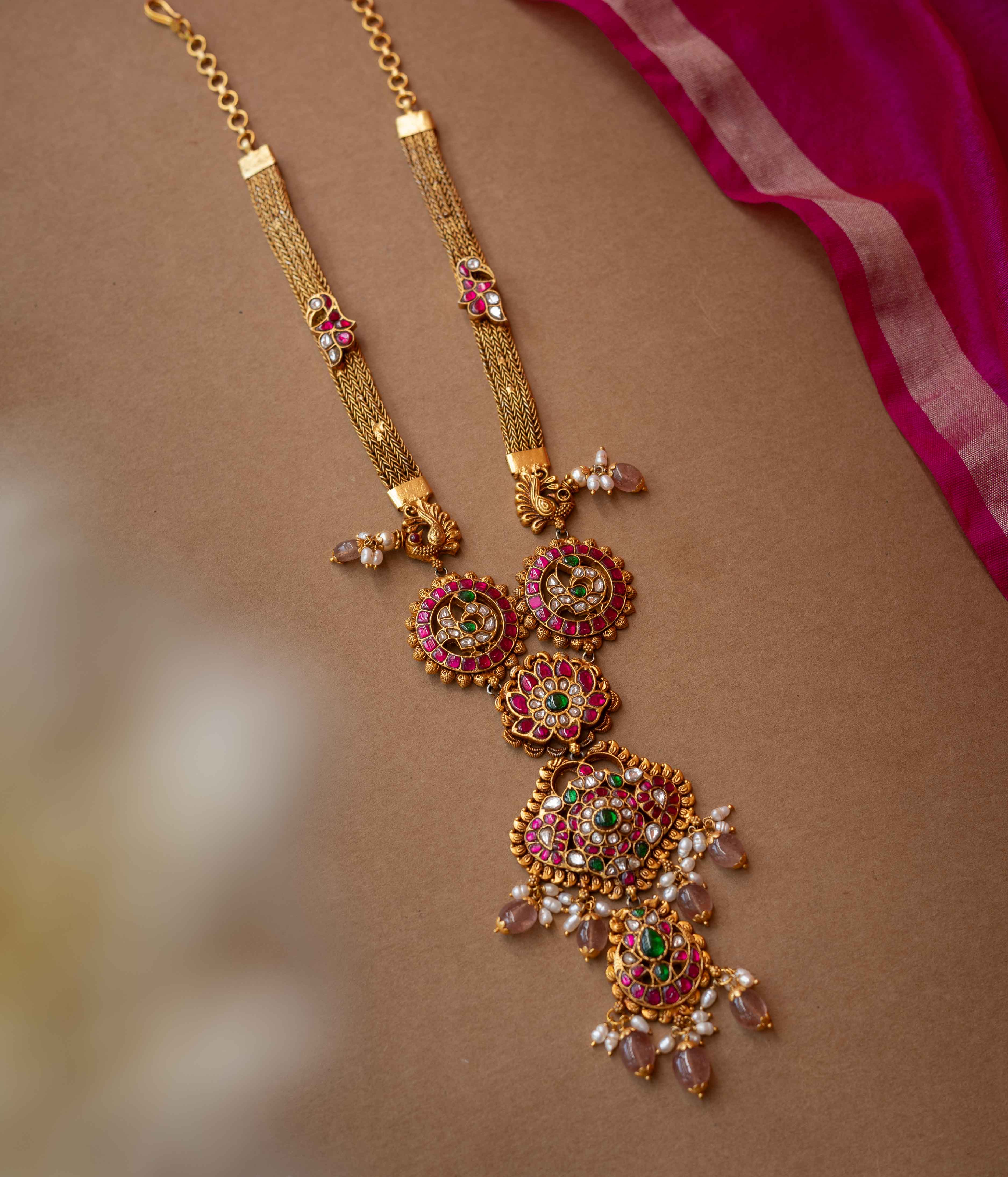 A multi-layered Kundan necklace with a central pendant and cascading strands of pearls and beads.
