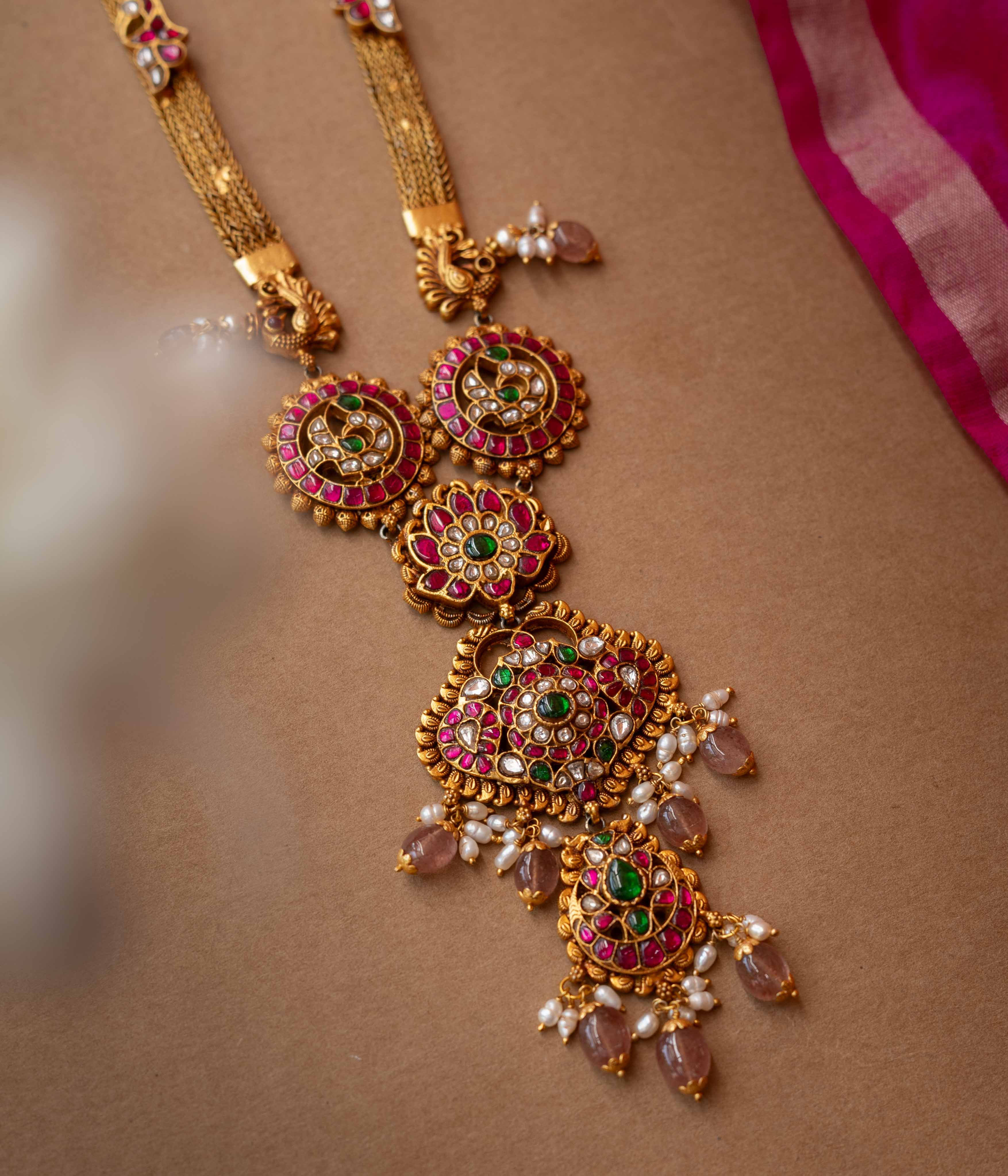 A multi-layered Kundan necklace with a central pendant and cascading strands of pearls and beads.
