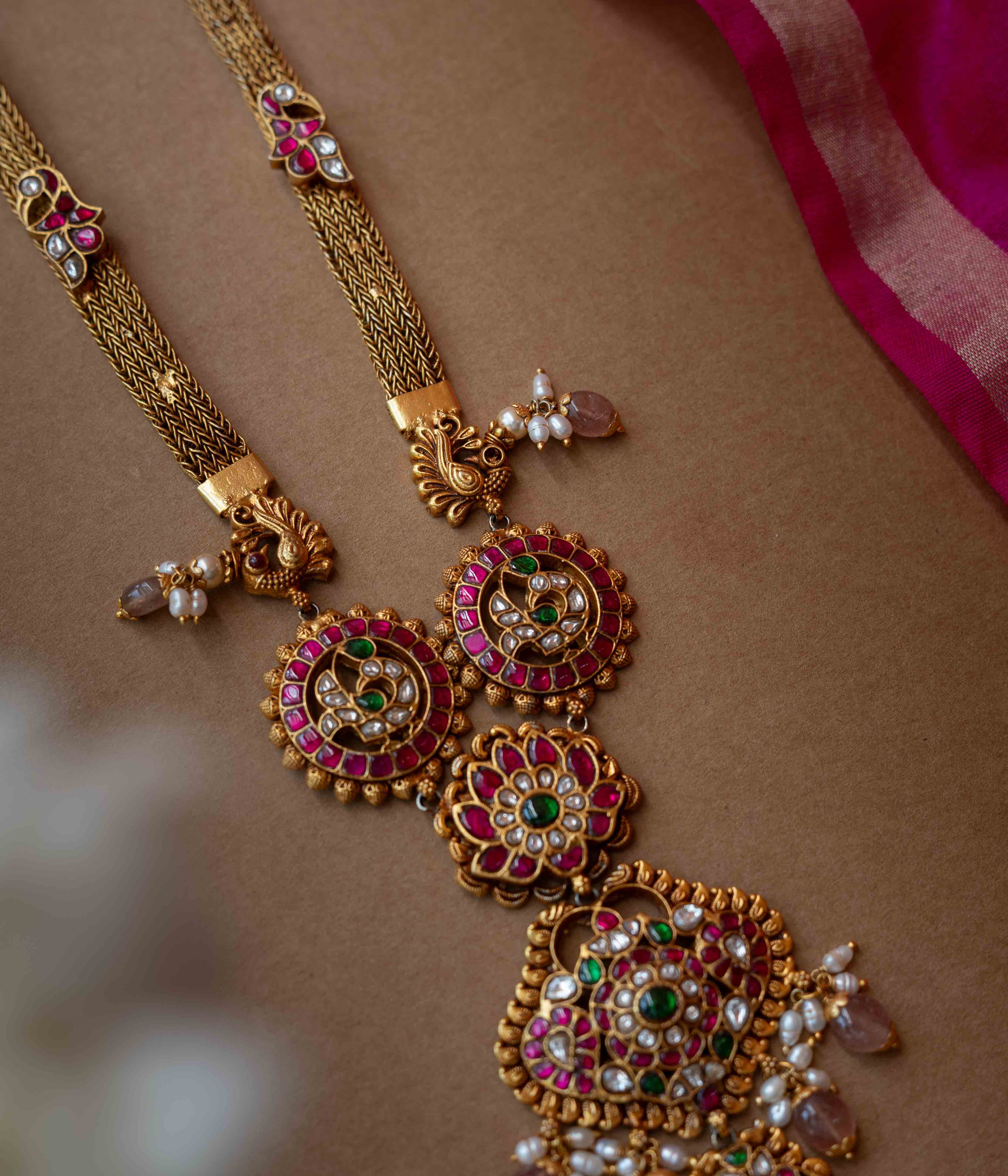 A multi-layered Kundan necklace with a central pendant and cascading strands of pearls and beads.
