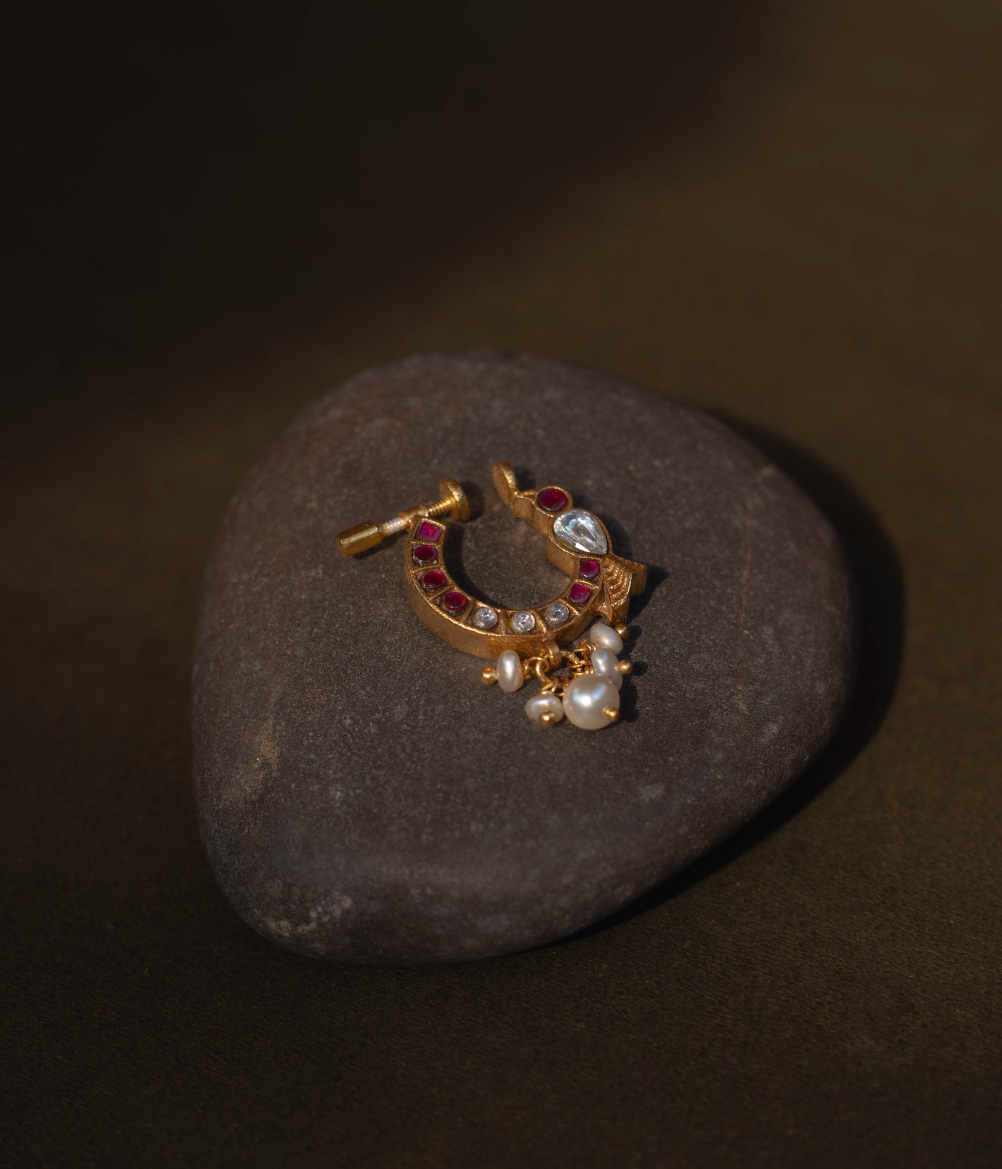 A delicate yet regal 92.5 sterling silver Rani Kemp Nath nosepin featuring vibrant red and white Kundan stones, a single teardrop-shaped white stone, and delicate dangling pearls set in a gold-plated framework, perfect for adding traditional Indian elegance.