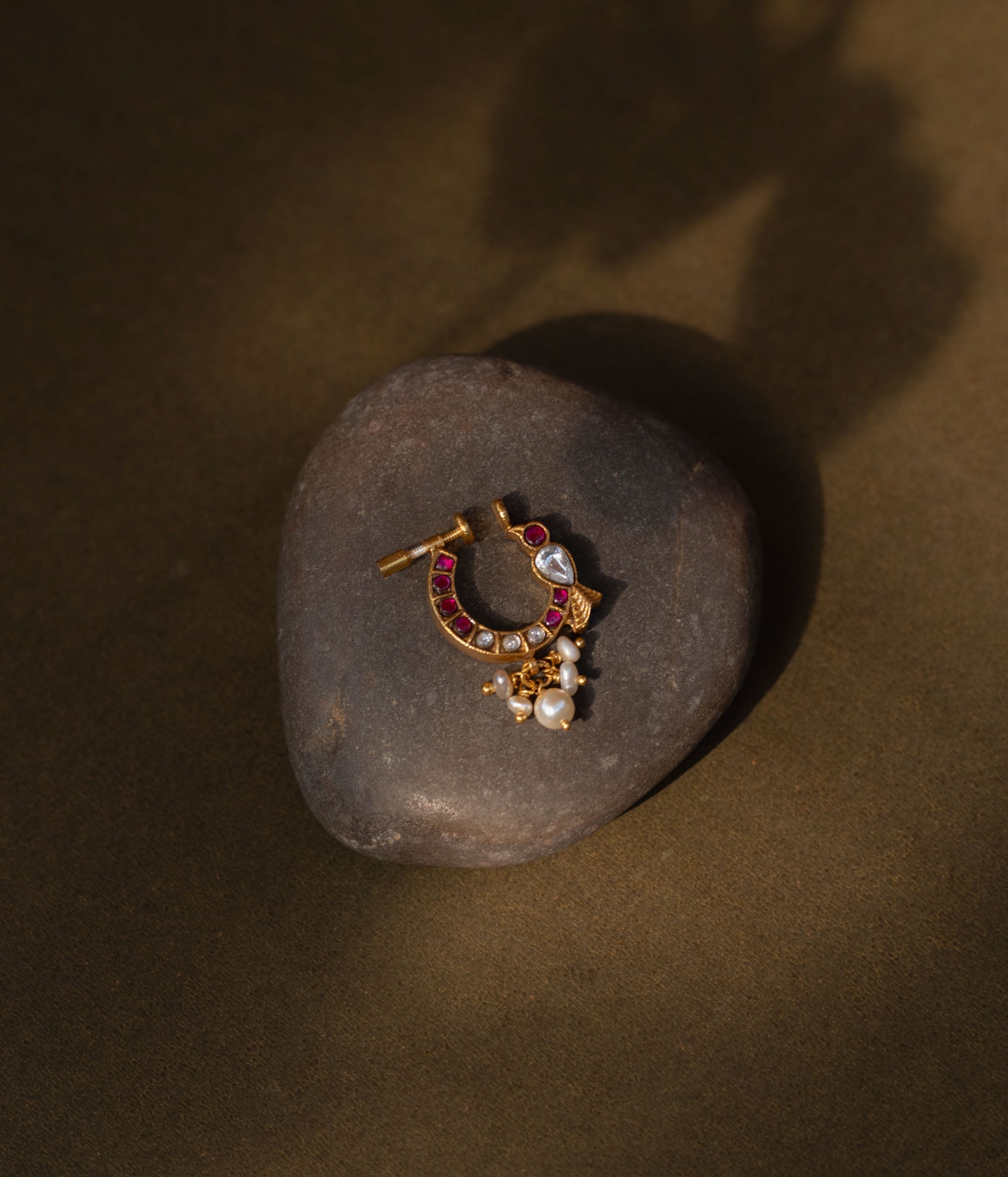 A delicate yet regal 92.5 sterling silver Rani Kemp Nath nosepin featuring vibrant red and white Kundan stones, a single teardrop-shaped white stone, and delicate dangling pearls set in a gold-plated framework, perfect for adding traditional Indian elegance.