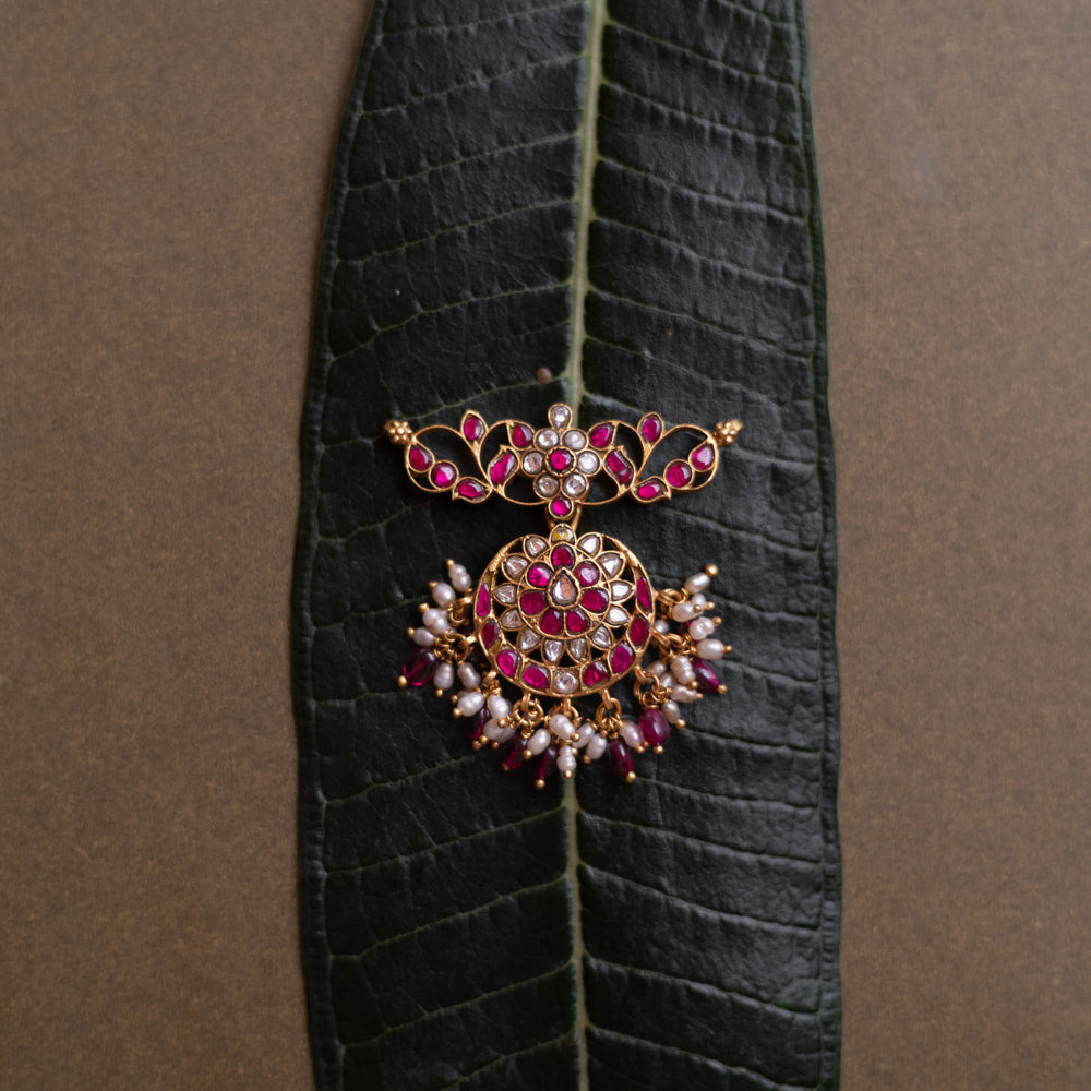 Lotus-inspired kundan pendant with red and white stones, pearl fringe, and circular floral design.