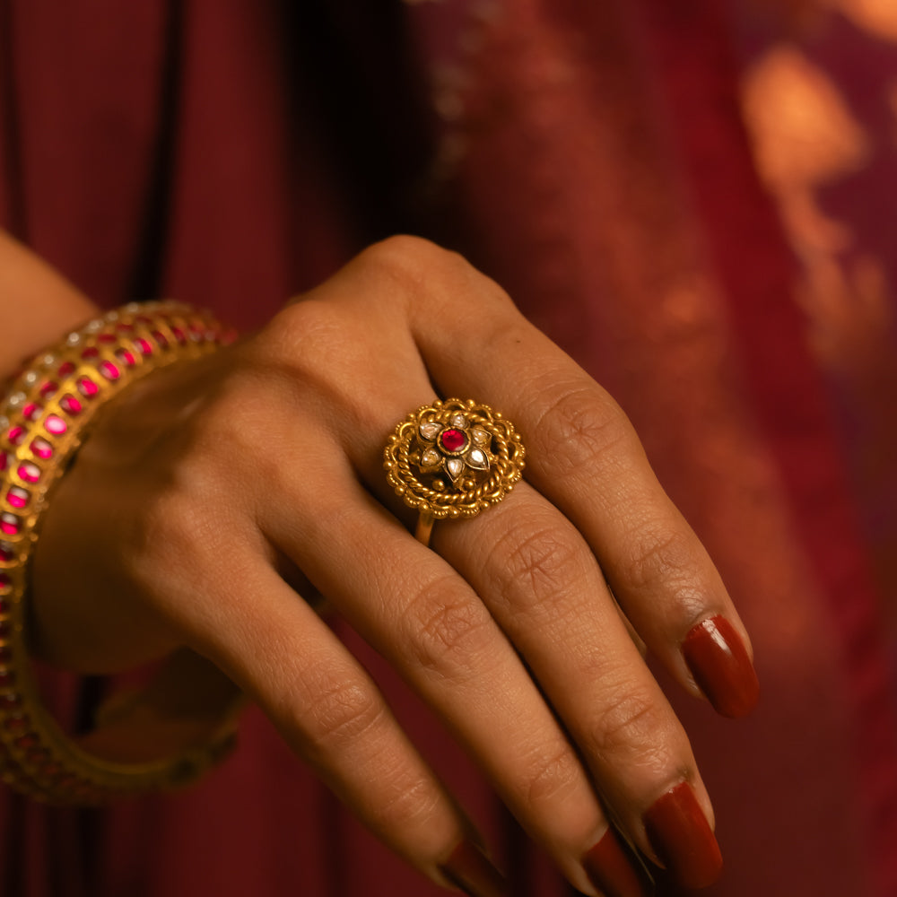 Gold floral ring with red and white Kundan stones, worn with matching bangle on hand.