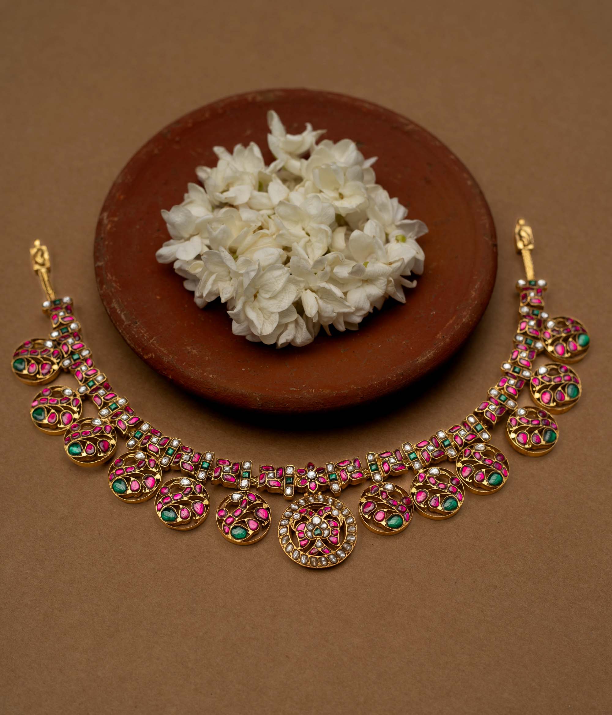 A 22ct gold-plated 92.5 sterling silver Chandra Kemp necklace, featuring circular motifs with pink and green Kemp stones, interspersed with pearls, and a central pearl-clustered pendant, ideal for festive occasions and celebrations.
