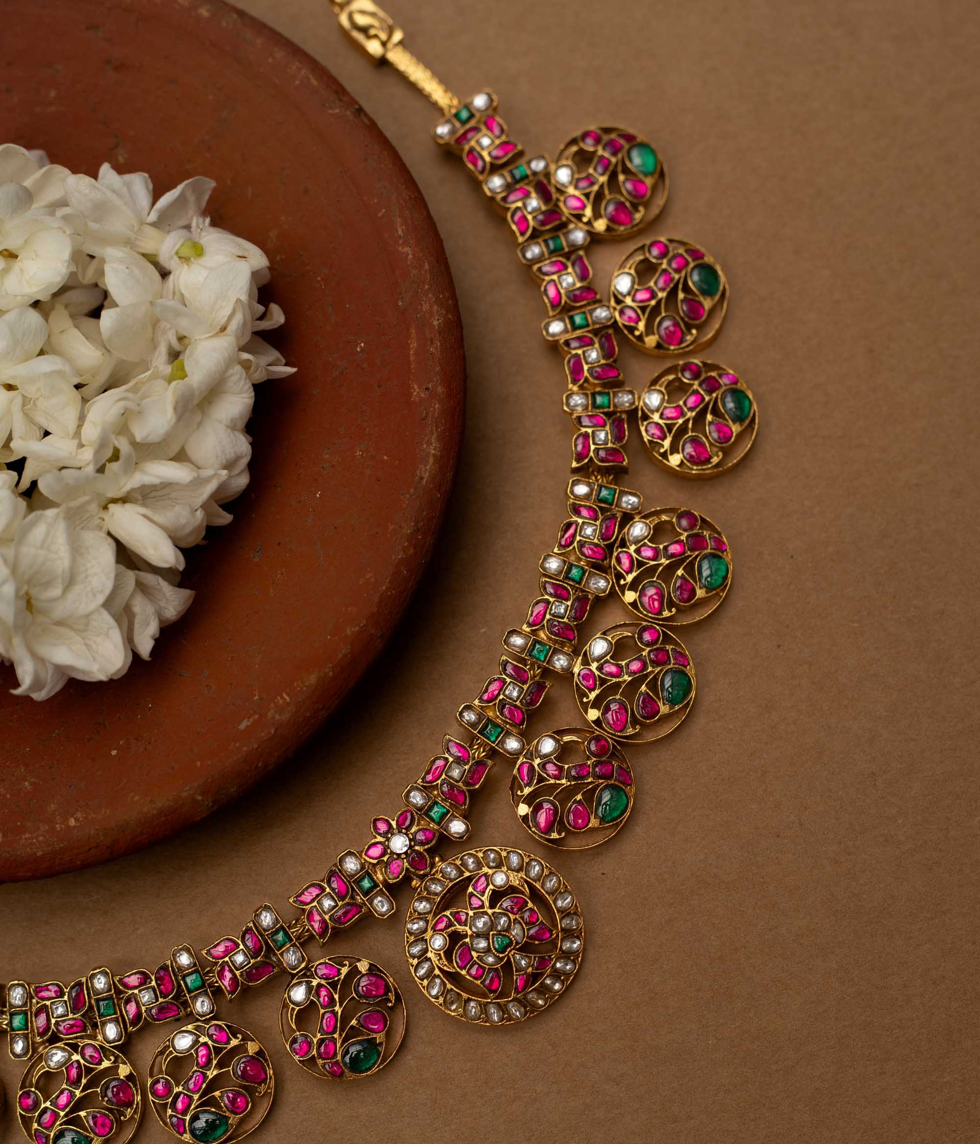 A 22ct gold-plated 92.5 sterling silver Chandra Kemp necklace, featuring circular motifs with pink and green Kemp stones, interspersed with pearls, and a central pearl-clustered pendant, ideal for festive occasions and celebrations.