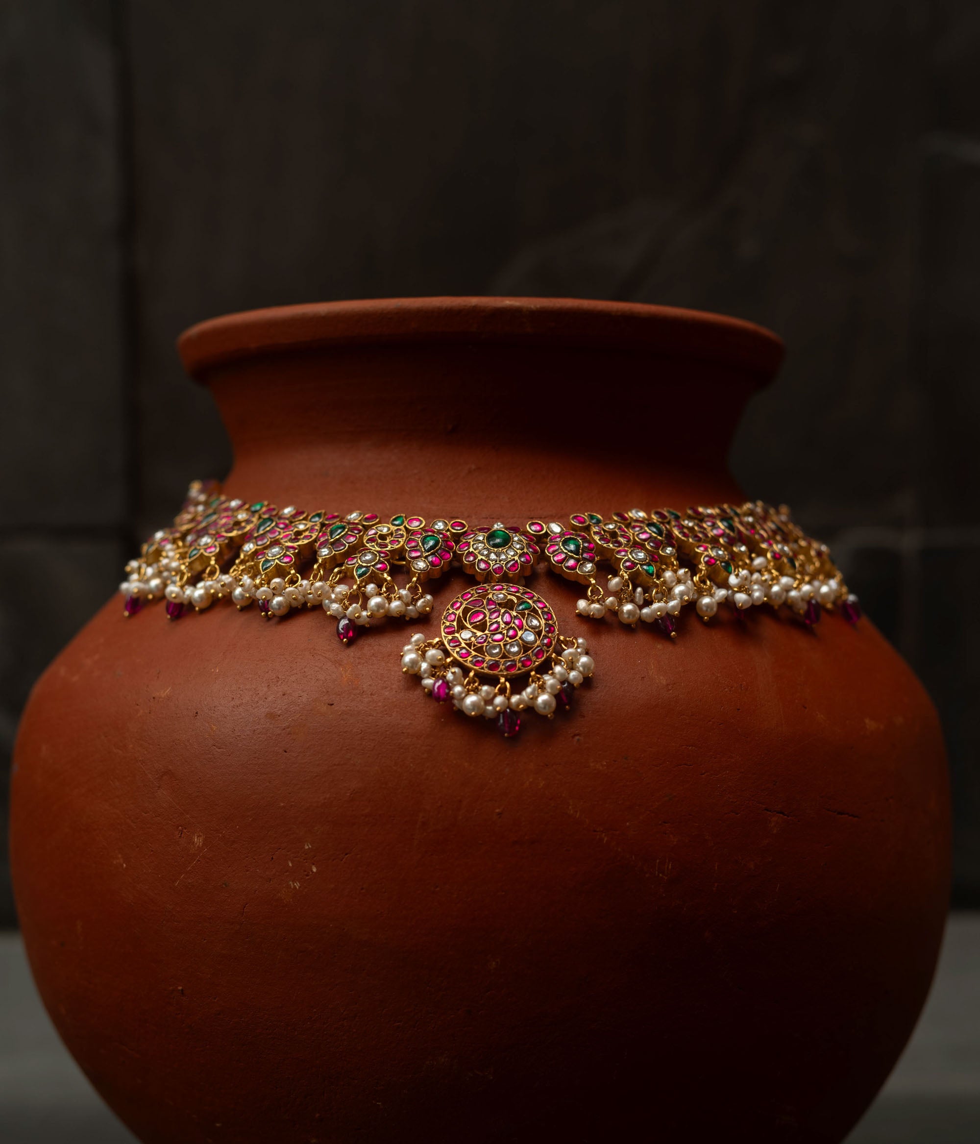A handcrafted 22ct gold-plated 92.5 sterling silver Kemp Lotus necklace featuring red, green, and white Kundan stones, red beads, and pearls, with a lotus-inspired central pendant, showcasing traditional South Indian jewelry craftsmanship.