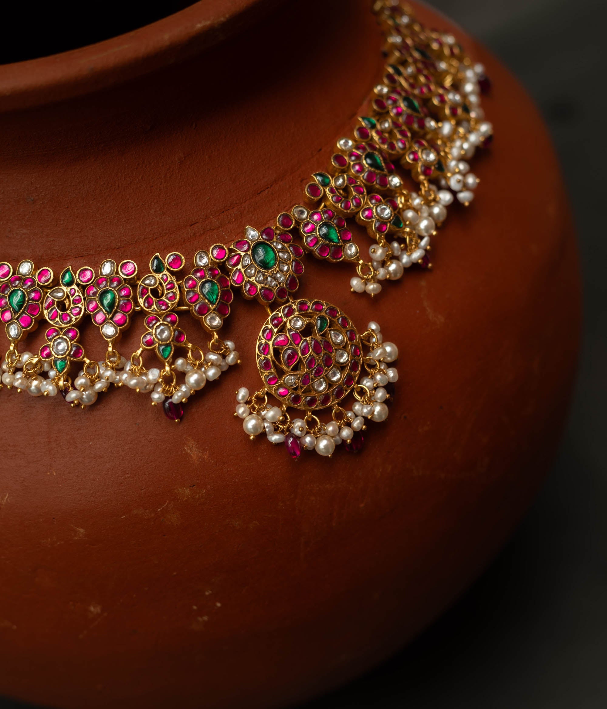 A handcrafted 22ct gold-plated 92.5 sterling silver Kemp Lotus necklace featuring red, green, and white Kundan stones, red beads, and pearls, with a lotus-inspired central pendant, showcasing traditional South Indian jewelry craftsmanship.