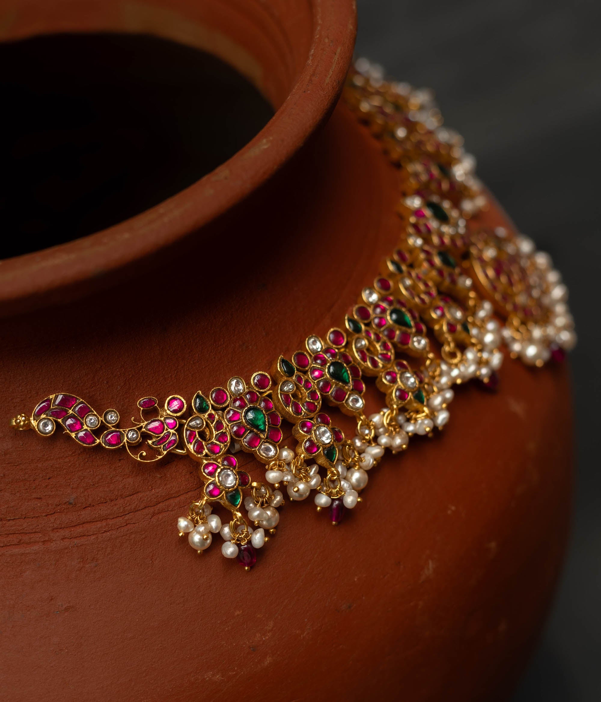 A handcrafted 22ct gold-plated 92.5 sterling silver Kemp Lotus necklace featuring red, green, and white Kundan stones, red beads, and pearls, with a lotus-inspired central pendant, showcasing traditional South Indian jewelry craftsmanship.