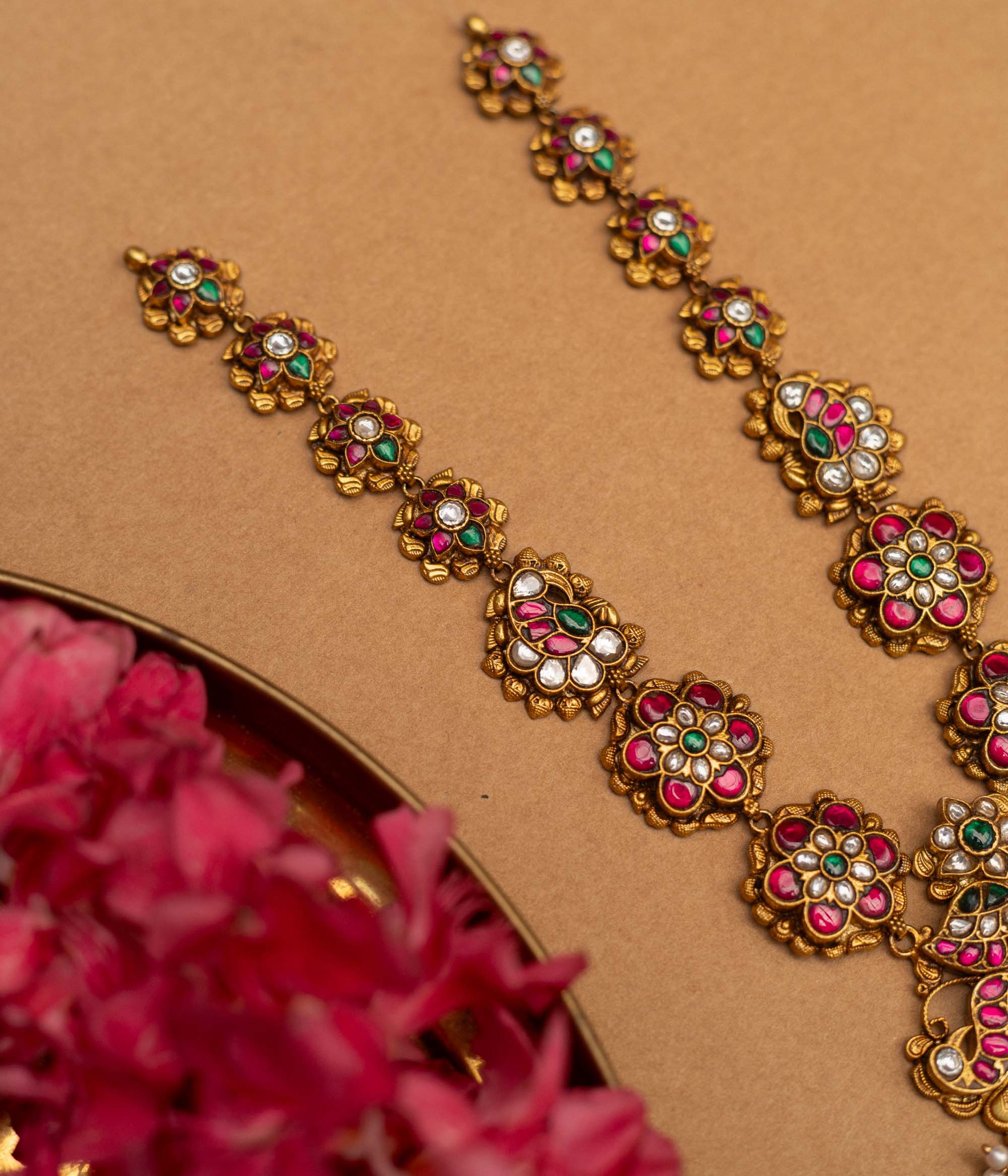 A 92.5 sterling silver Blossom Radiance Peacock Necklace with an antique finish, featuring a pendant adorned with twin peacocks, dazzling kundan stones, and vibrant pink and green accents, a floral-link chain, and dangling emerald-green beads and pearls, perfect for weddings, temple occasions, and cultural festivities.