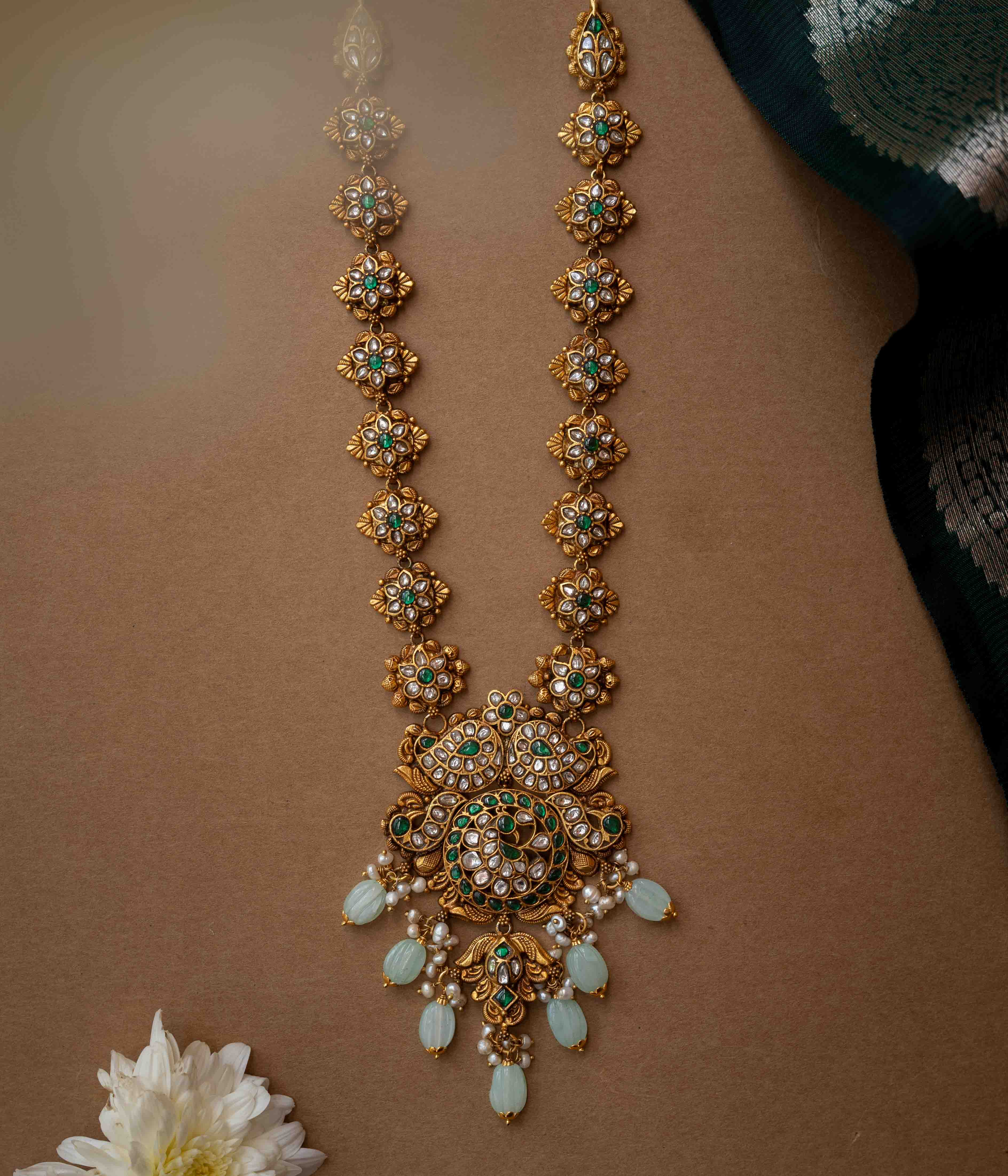 A multi-layered necklace with a central Kundan pendant and cascading strands of pearls and beads.
