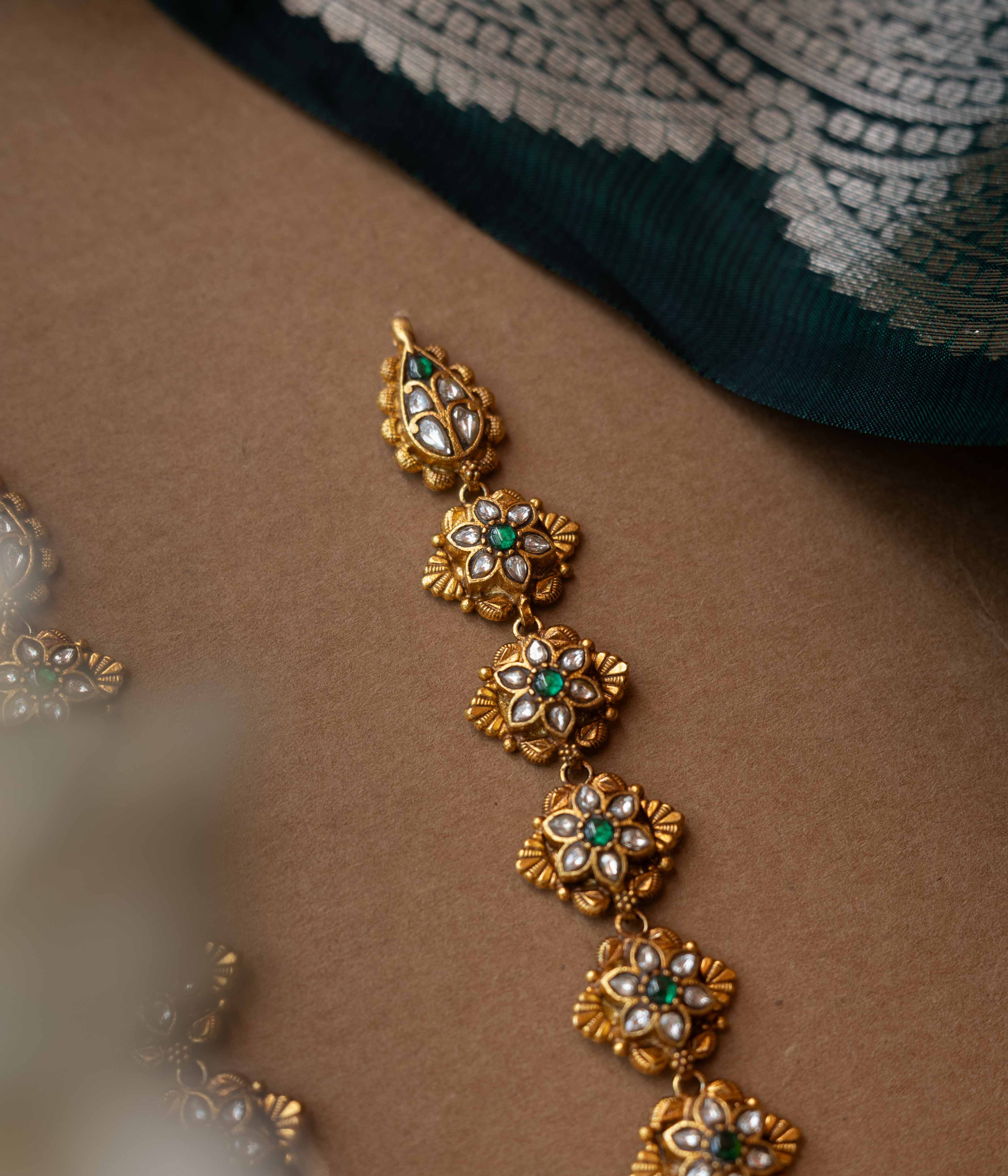 A multi-layered necklace with a central Kundan pendant and cascading strands of pearls and beads.
