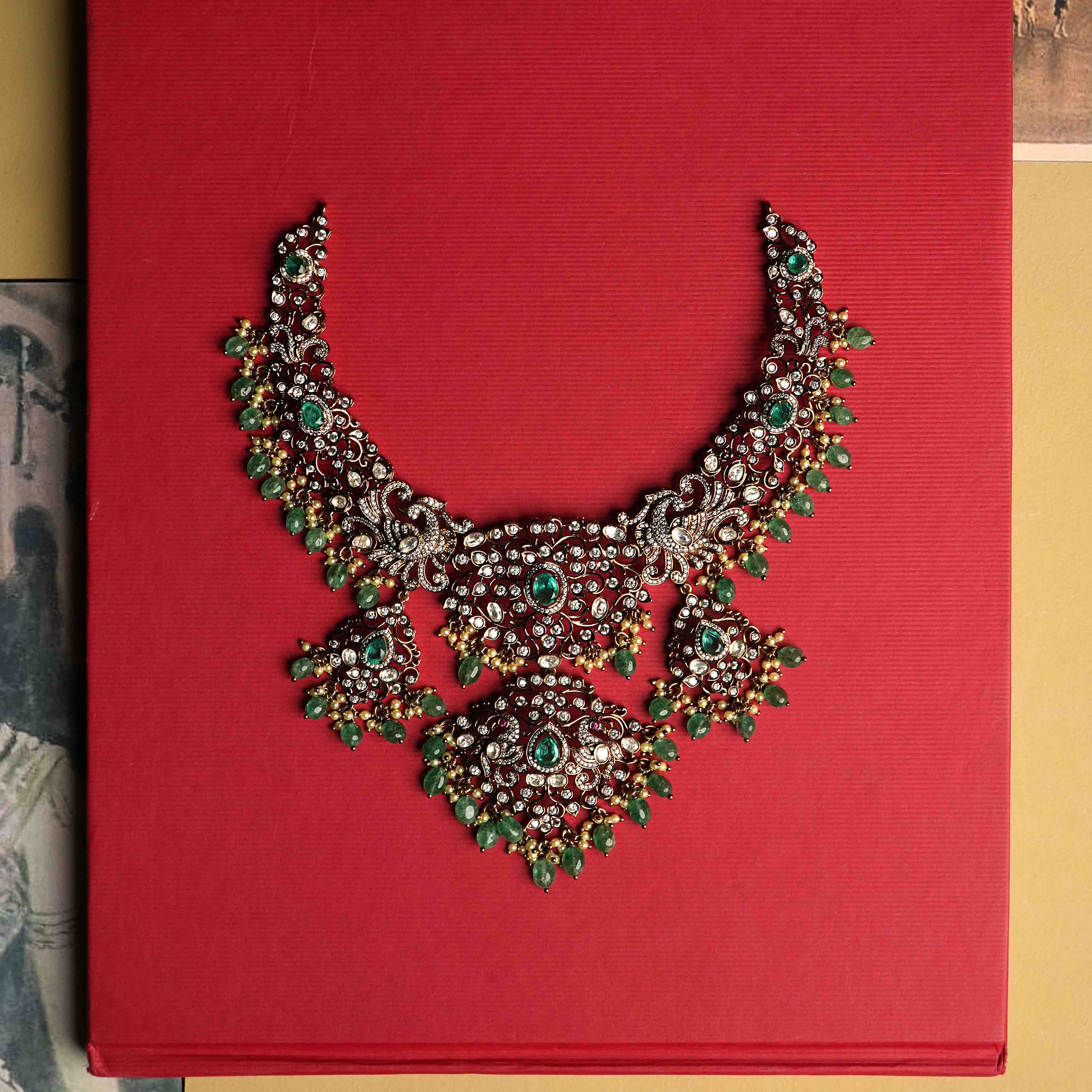 An elaborate moissanite necklace handcrafted from 92.5 sterling silver with 14ct dark antique gold plating, featuring CZ stones, a green gemstone, polki stones, and pearls, finished in a Victorian style, with cultured emerald and pearl dangles evoking vintage luxury.