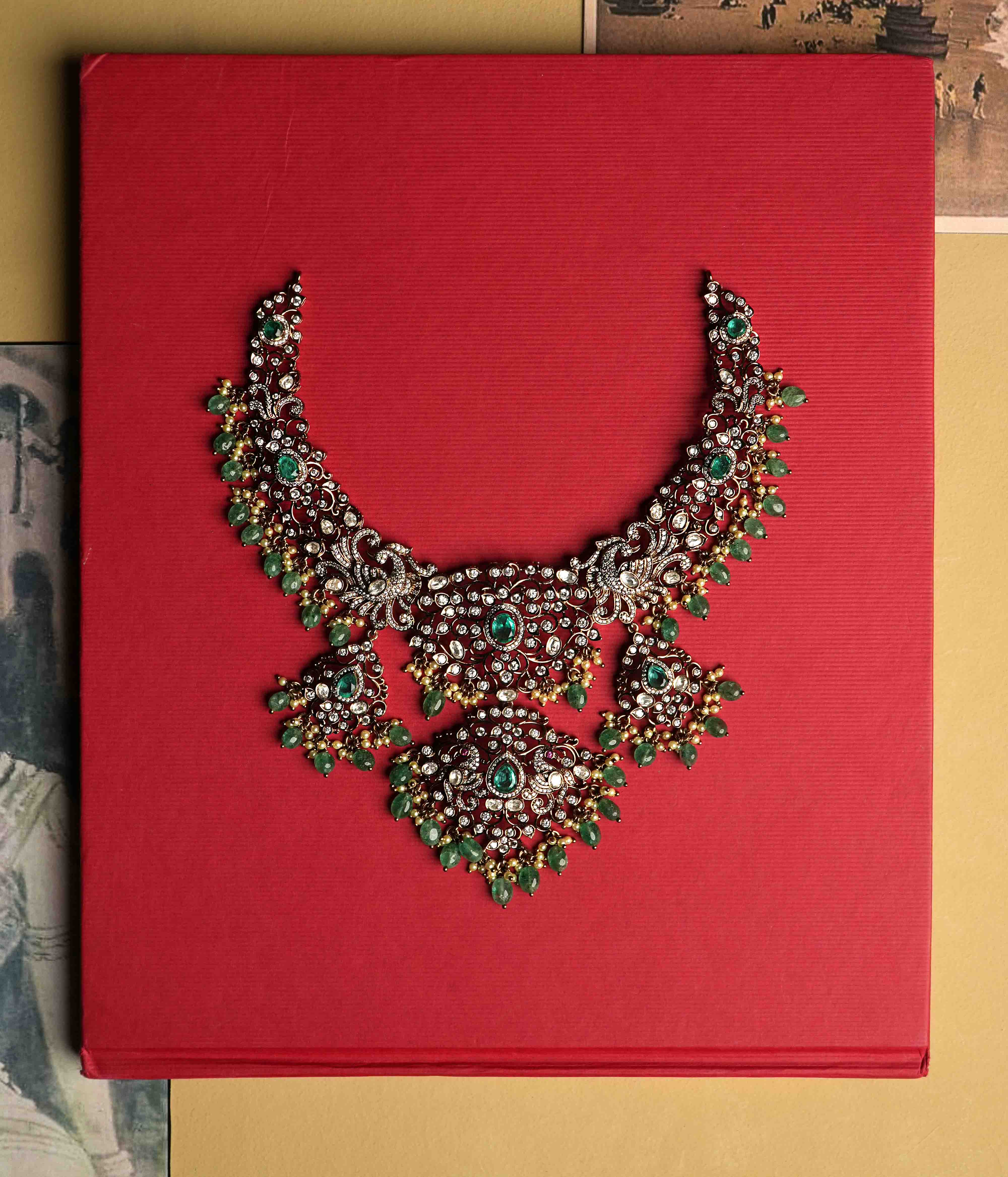 An elaborate moissanite necklace handcrafted from 92.5 sterling silver with 14ct dark antique gold plating, featuring CZ stones, a green gemstone, polki stones, and pearls, finished in a Victorian style, with cultured emerald and pearl dangles evoking vintage luxury.
