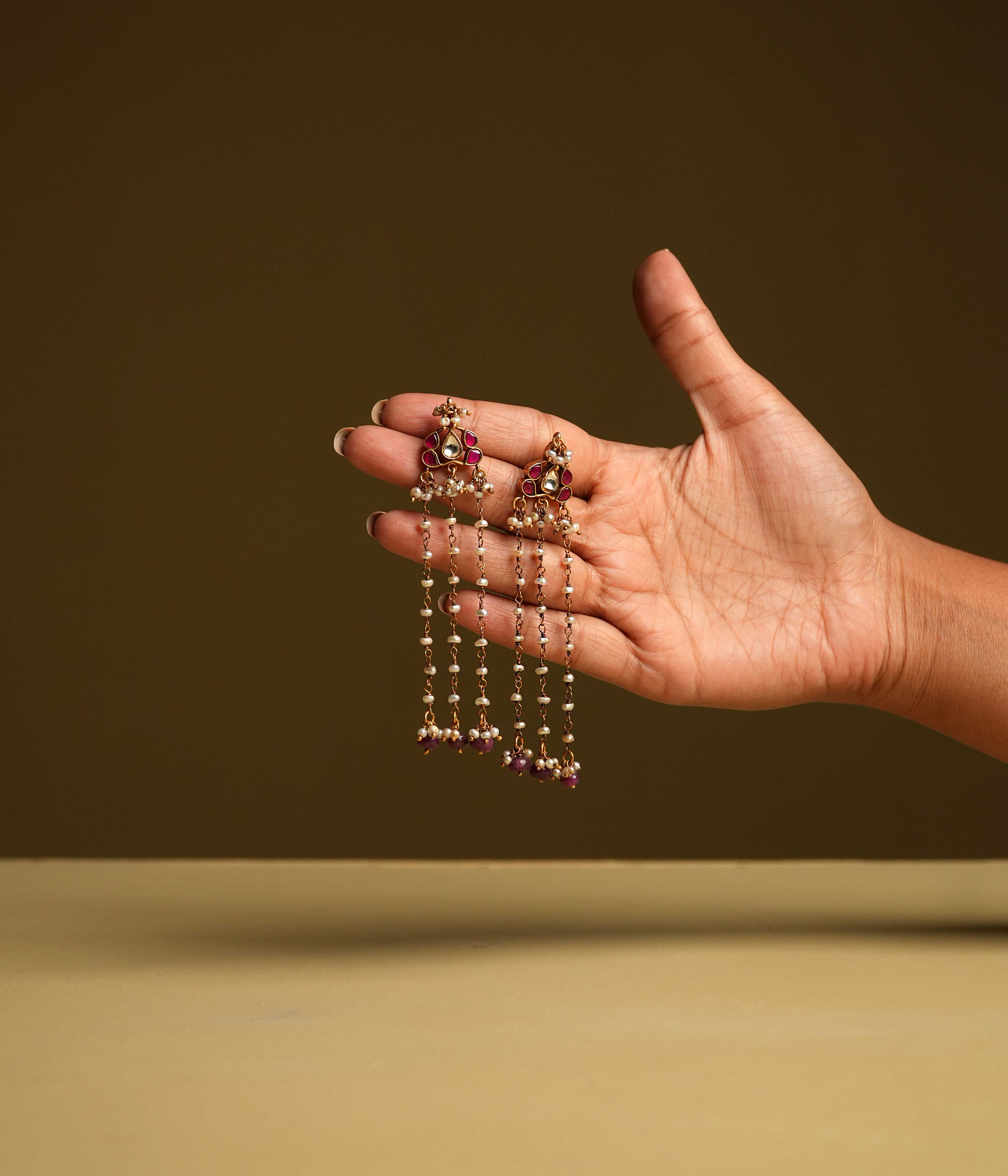 Keshini Earrings made of 92.5 sterling silver with screw-type fastening. Featuring red and white Kundan stones, red beads, and pearls, this exquisite pair exudes celestial elegance and timeless charm, designed for the woman who captivates with every glance.