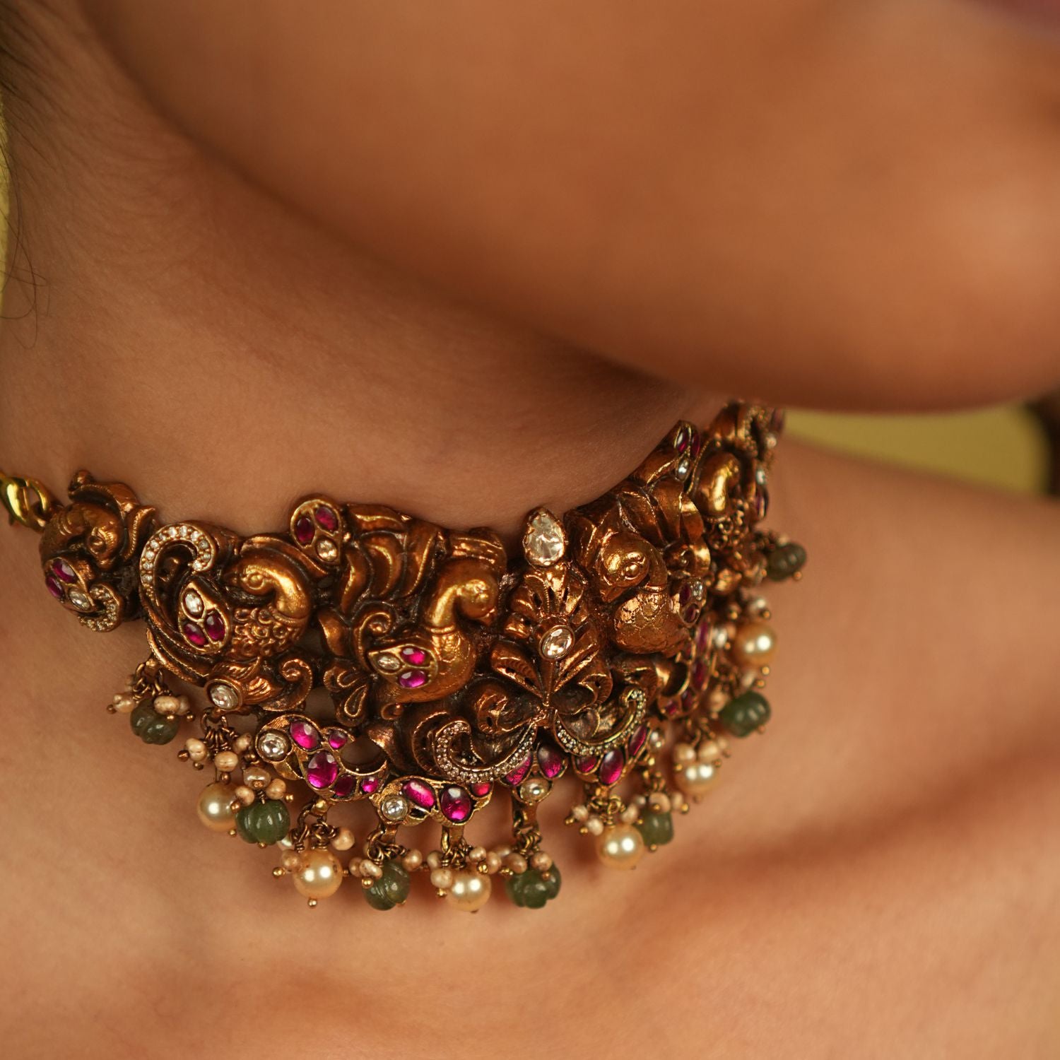A peacock-inspired choker adorned with red, white, and green kundan, polki, and CZ stones, with delicate green and white bead droplets. More than an adornment, it is a timeless tribute to culture and divine beauty.
