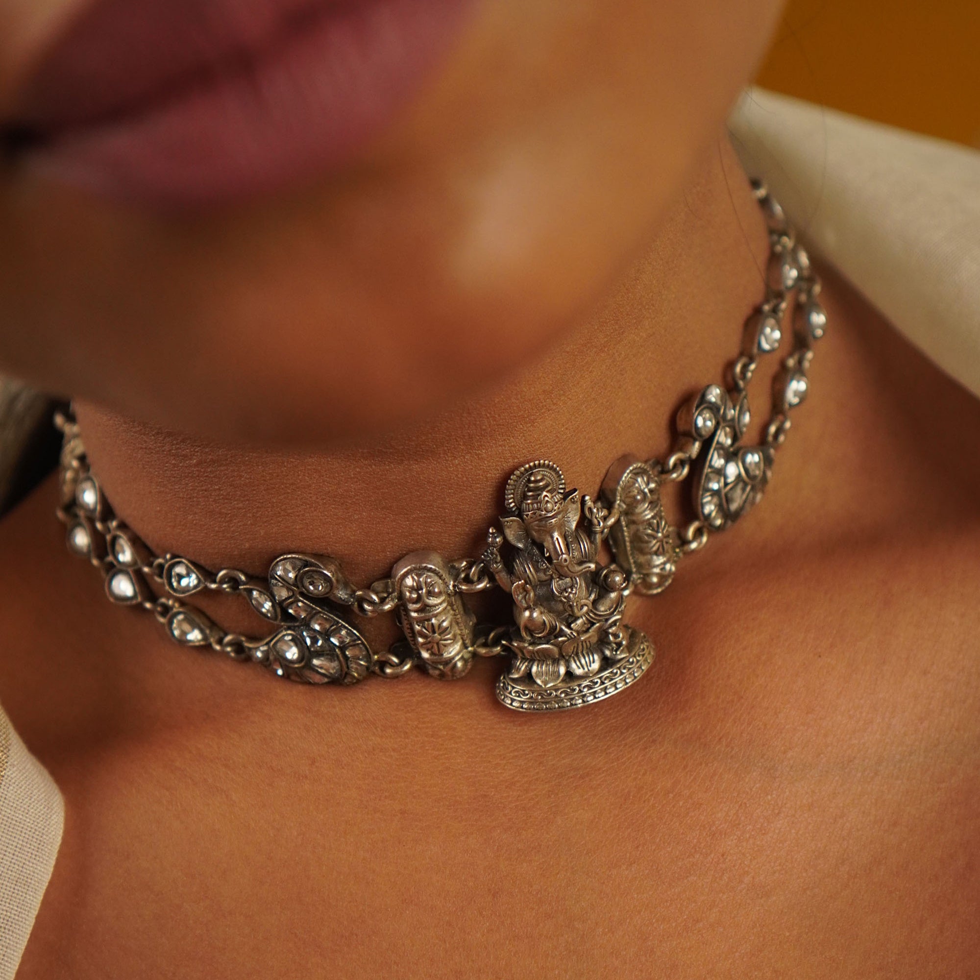 Silver chain necklace with intricate designs worn by a person