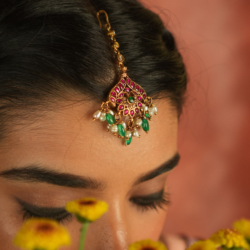 Bridal blossom! Red, white, and green lotus maangtika: A symbol of grace and renewal, radiating timeless elegance.