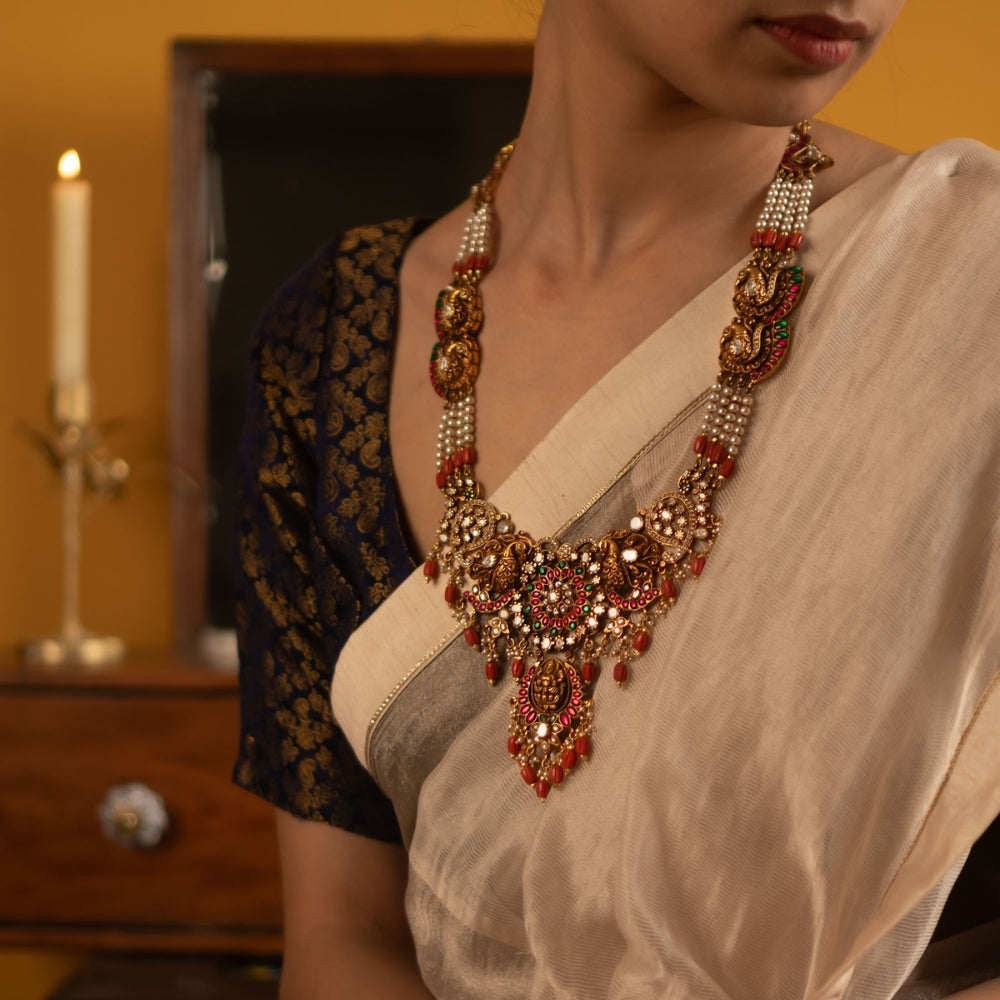 The Manya necklace, embellished with radiant red, white, and green kundan stones along with delicate red beads, captures the allure of a bygone era. Adorned with polkis, it beautifully merges tradition with timeless elegance.