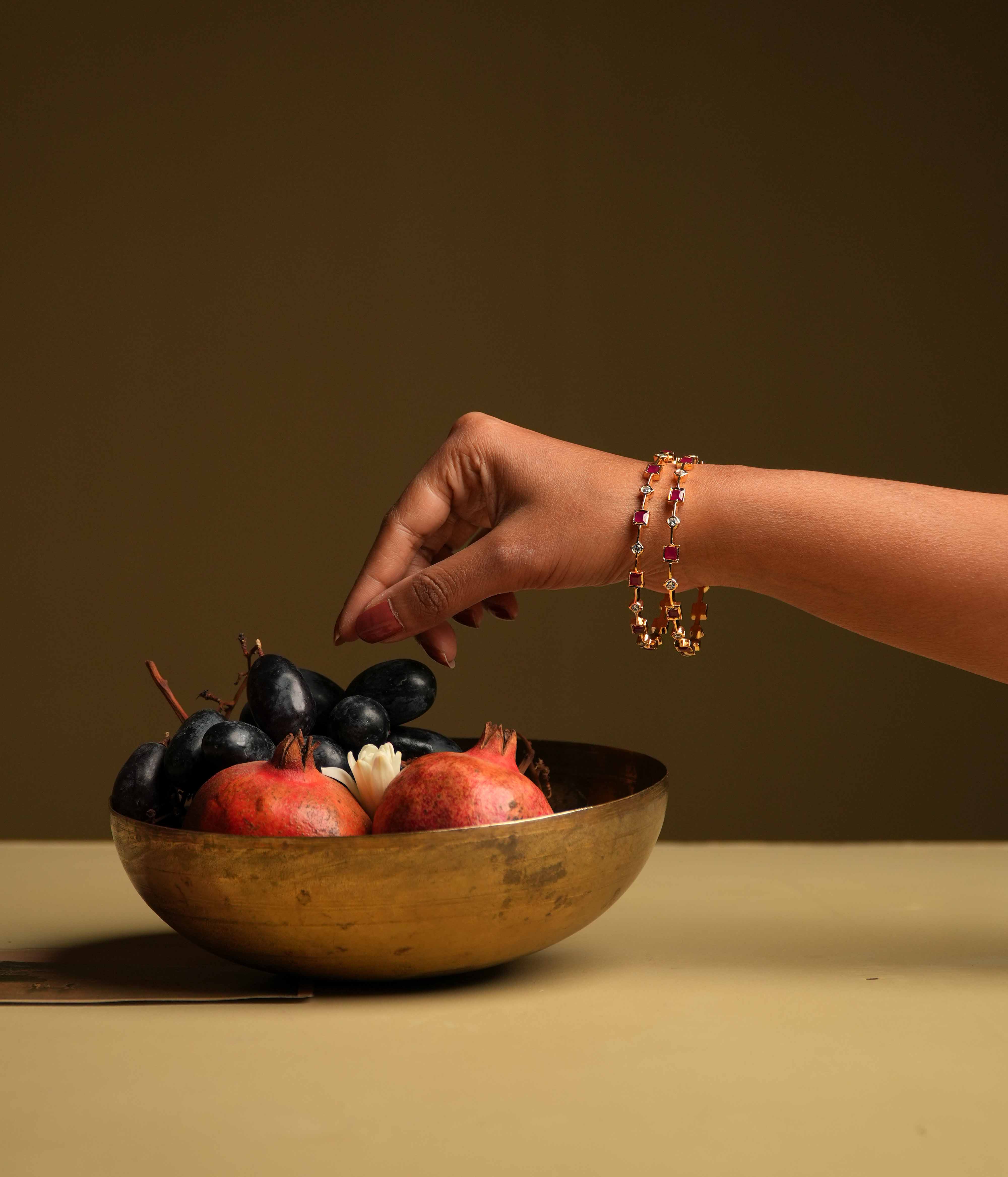 A minimalist 92.5 sterling silver bangle with an insert type closure, featuring alternating square-cut red gemstones and round white stones, creating a delicate dance of color and light, perfect for the woman who values sleek sophistication and a touch of subtle glamour.