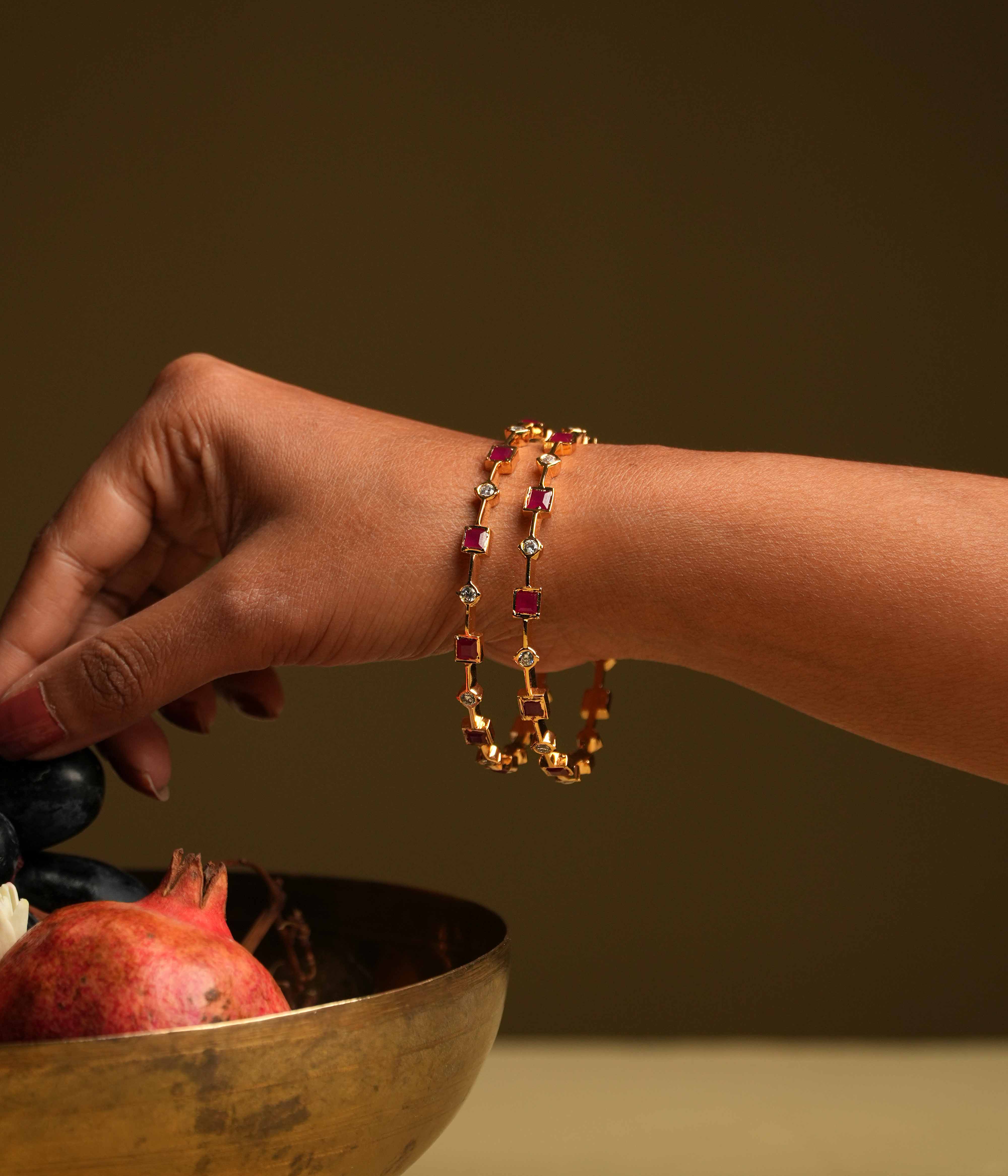 A minimalist 92.5 sterling silver bangle with an insert type closure, featuring alternating square-cut red gemstones and round white stones, creating a delicate dance of color and light, perfect for the woman who values sleek sophistication and a touch of subtle glamour.