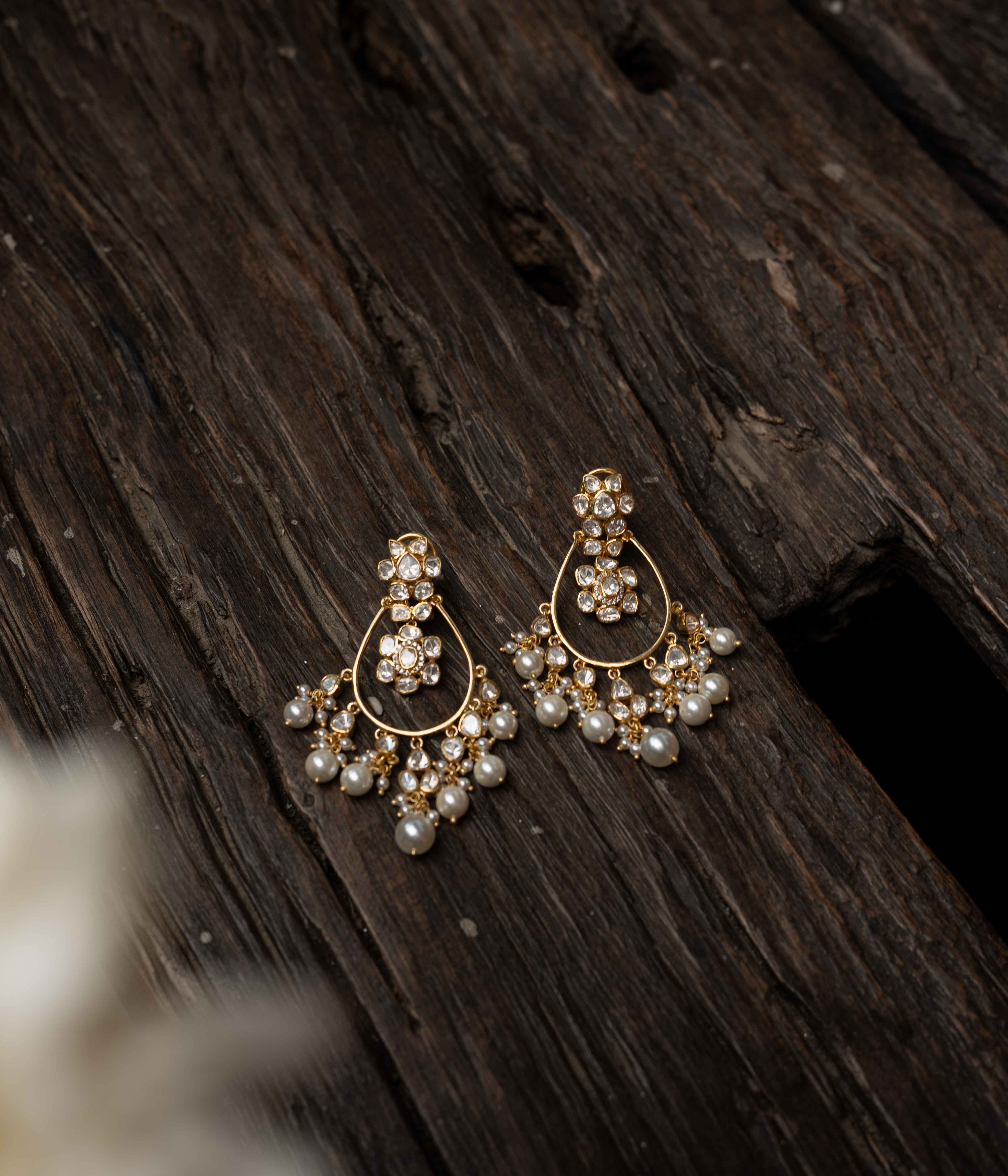 Intricate jhumka earrings with clear stones and dangling pearls.