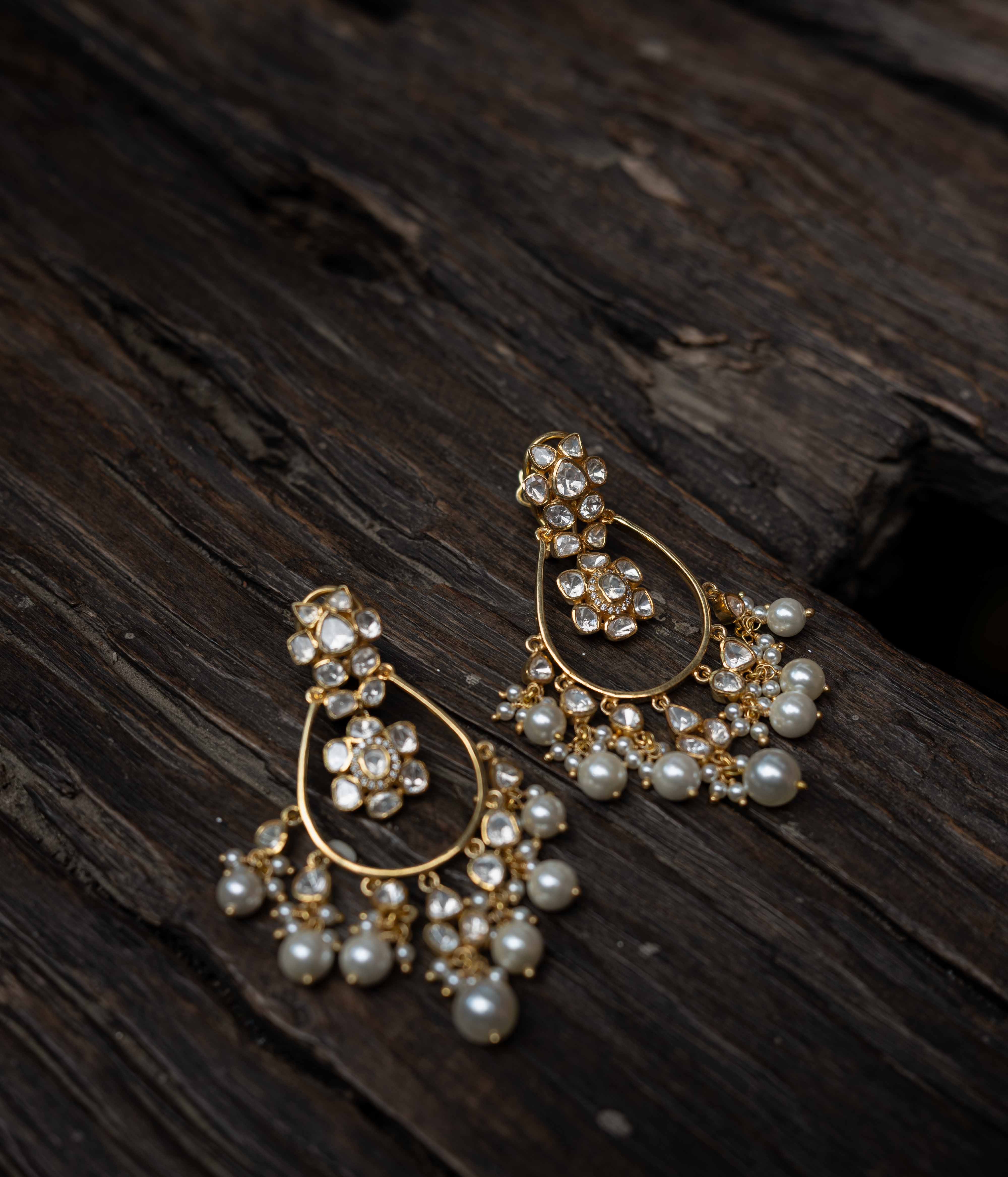 Intricate jhumka earrings with clear stones and dangling pearls.