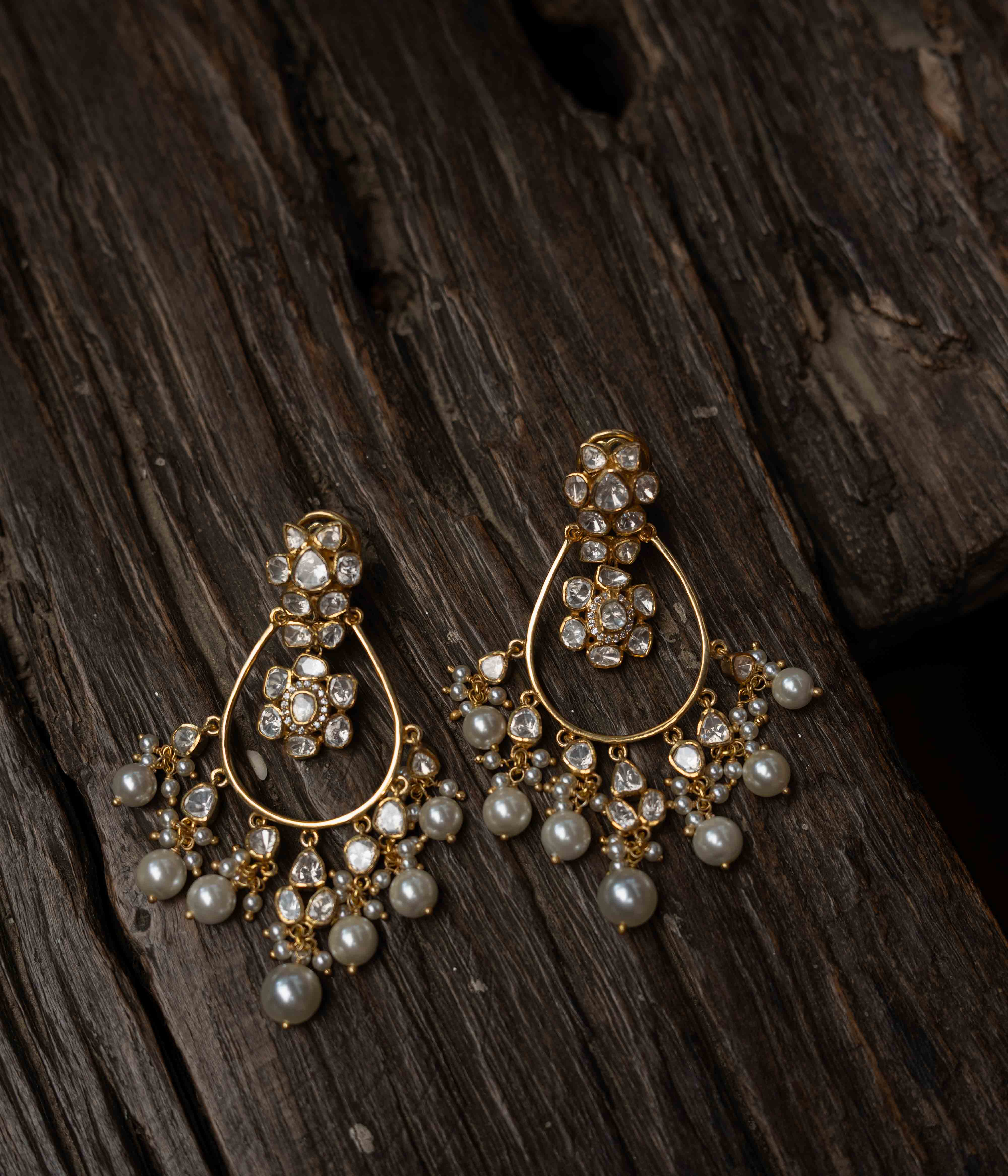 Intricate jhumka earrings with clear stones and dangling pearls.