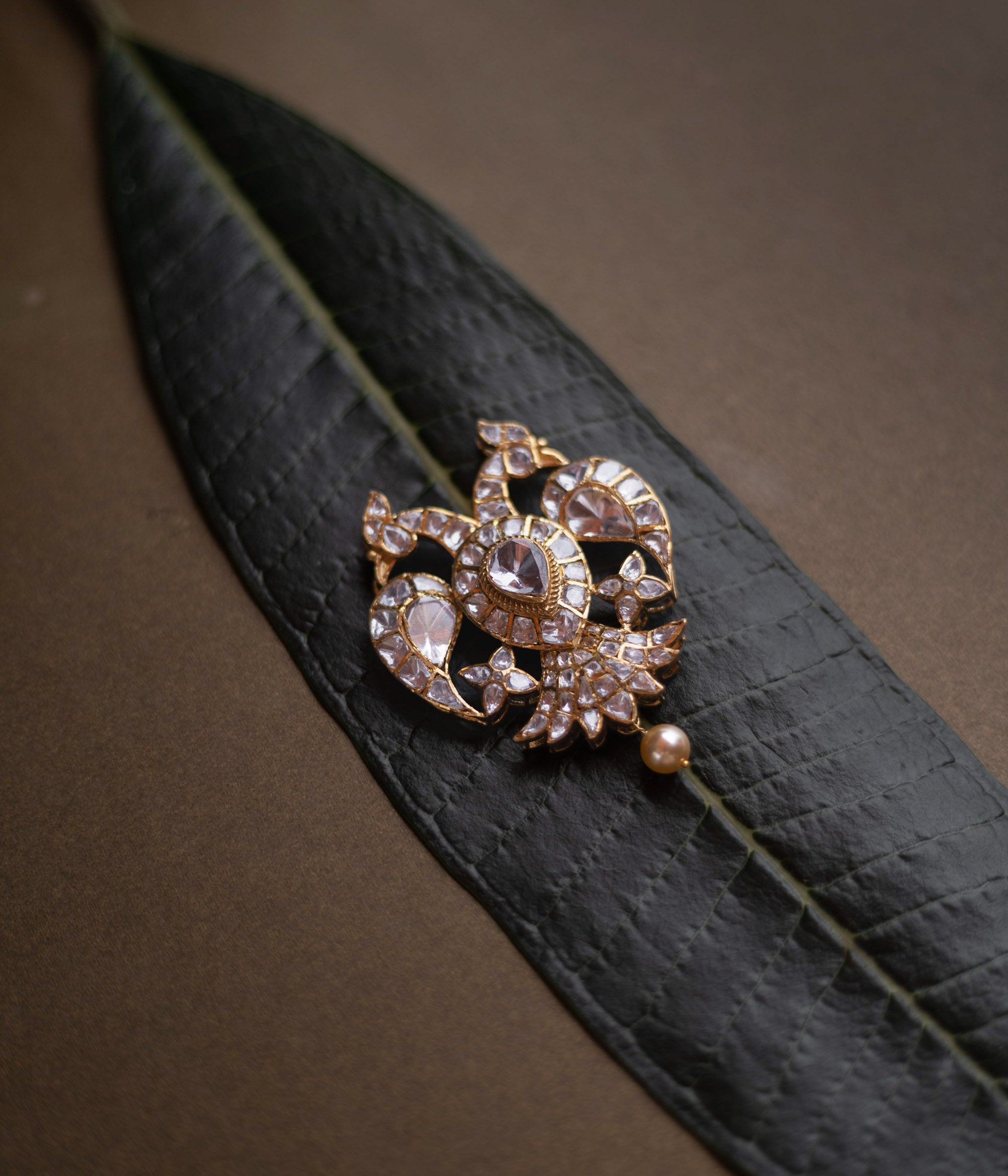 Antique gold pendant featuring twin peacocks, set with moissanite polki stones, and a single pearl drop.