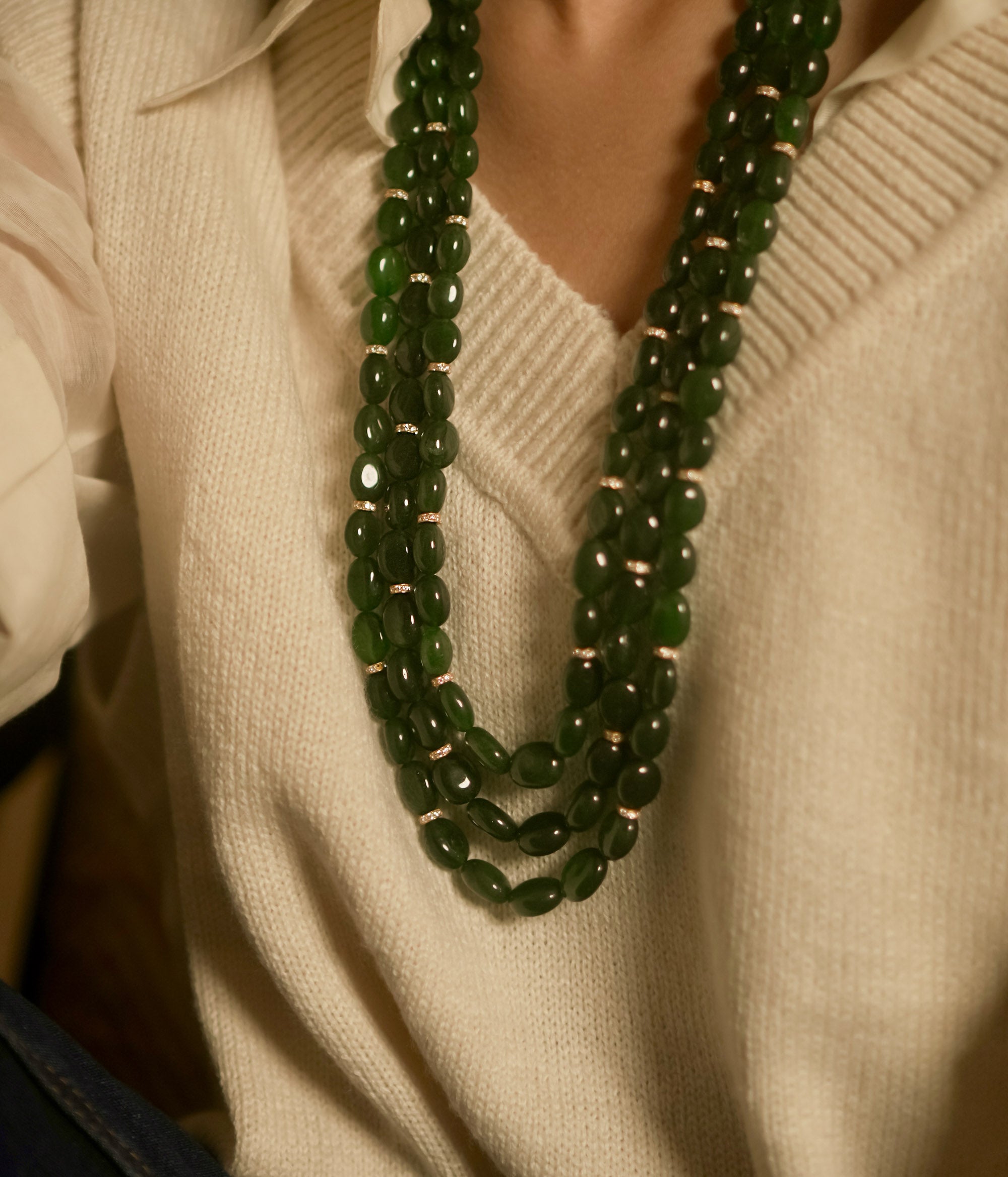 Resting in an elegant display, the triple-layered green strawberry necklace glows with a radiant allure, its rich hues catching the light with every delicate movement.