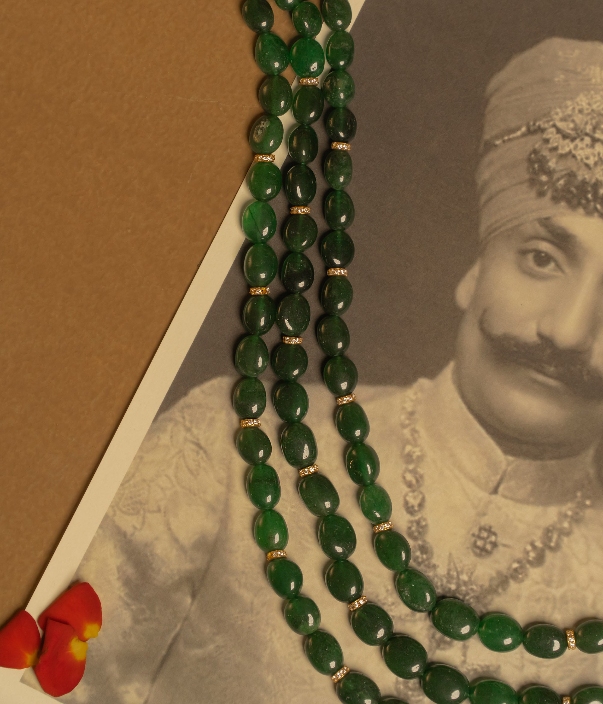 Resting in an elegant display, the triple-layered green strawberry necklace glows with a radiant allure, its rich hues catching the light with every delicate movement.