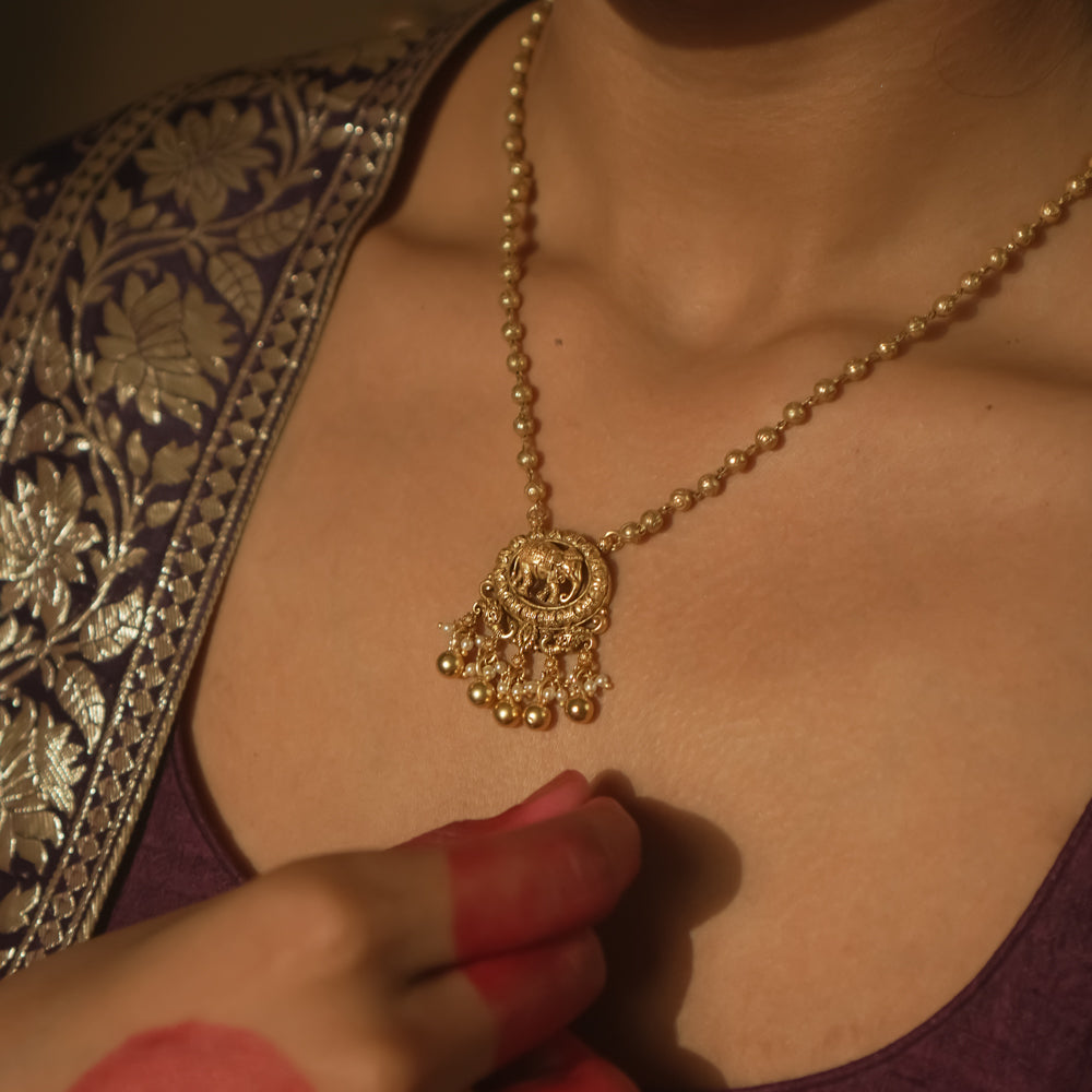 Gold necklace with a delicate chain and a pendant with an elephant silhouette.