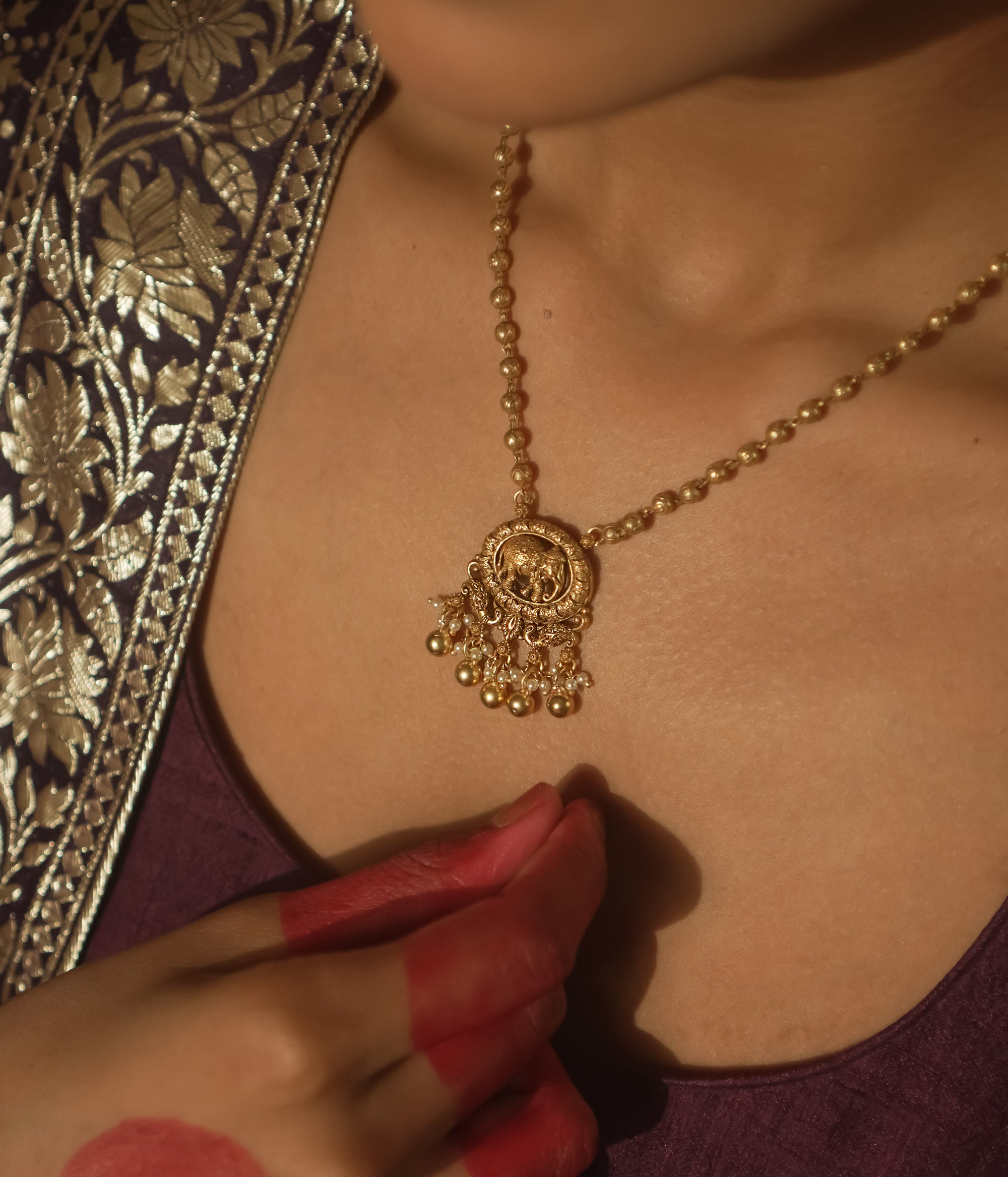 Gold necklace with a delicate chain and a pendant with an elephant silhouette.