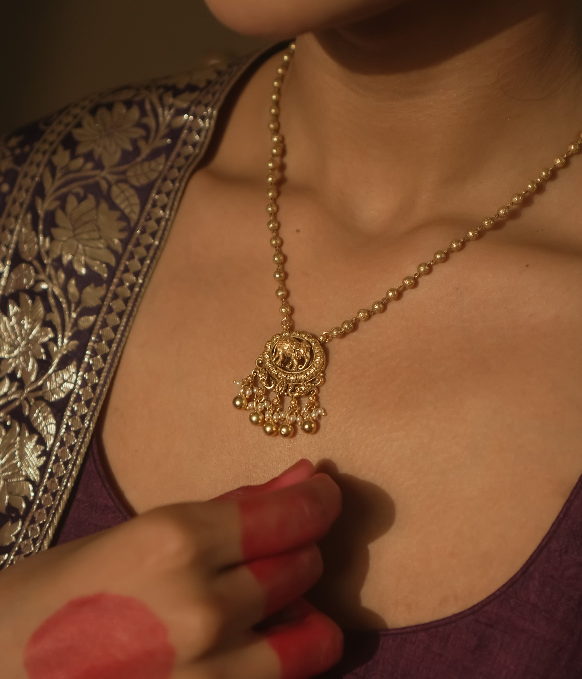 Gold necklace with a delicate chain and a pendant with an elephant silhouette.
