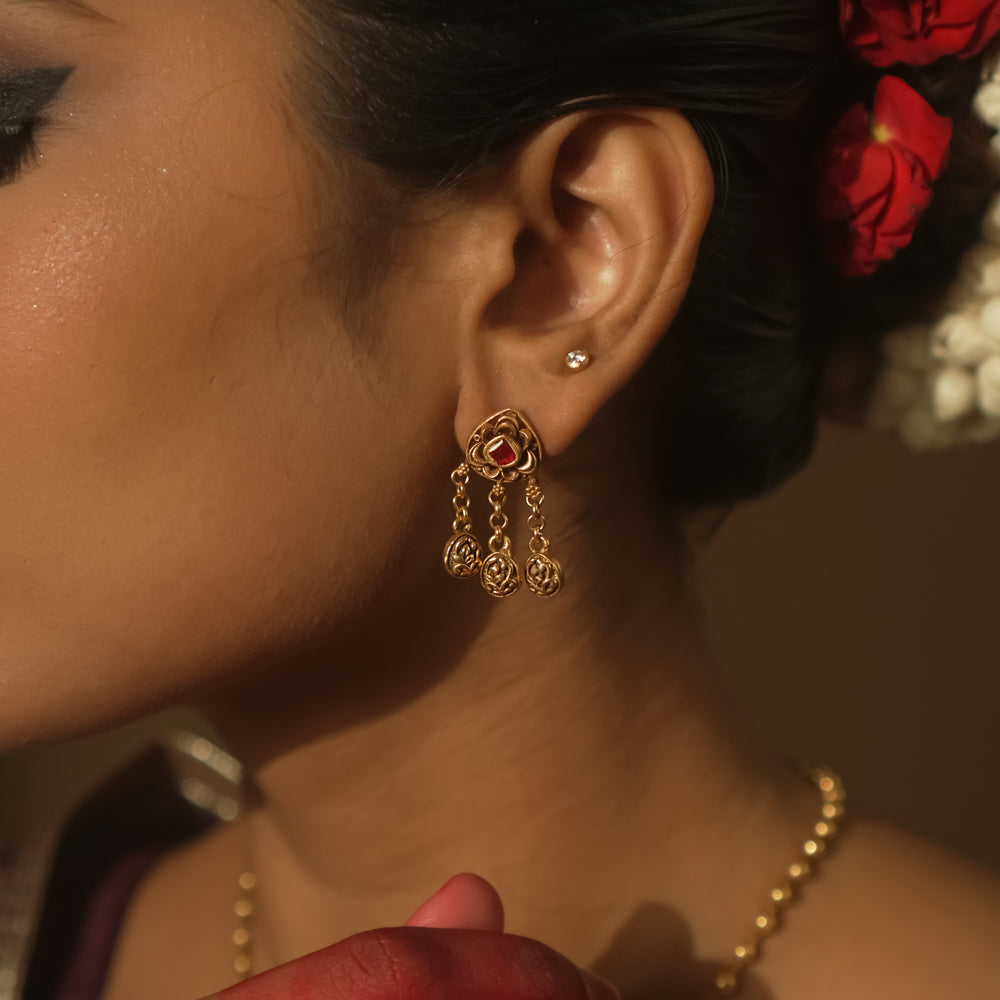 Earrings with chains of tiny coins and a central ruby red Kundan stone.