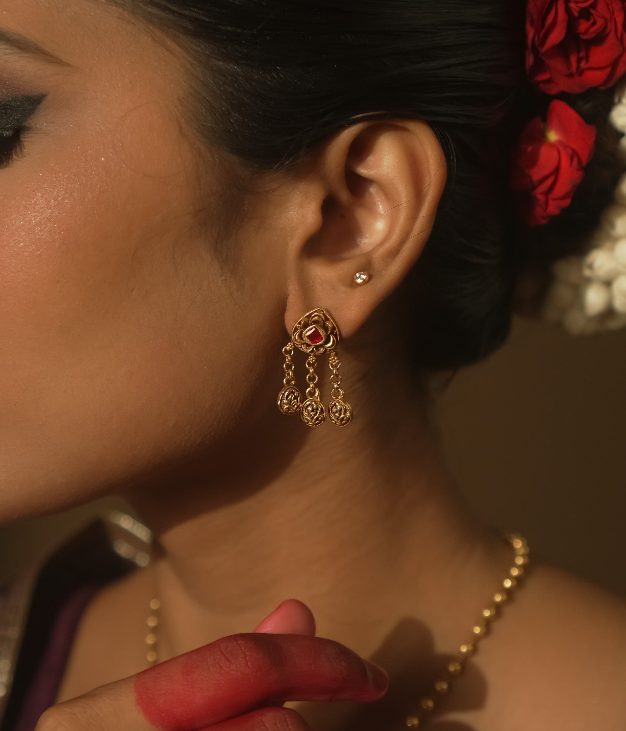 Earrings with chains of tiny coins and a central ruby red Kundan stone.
