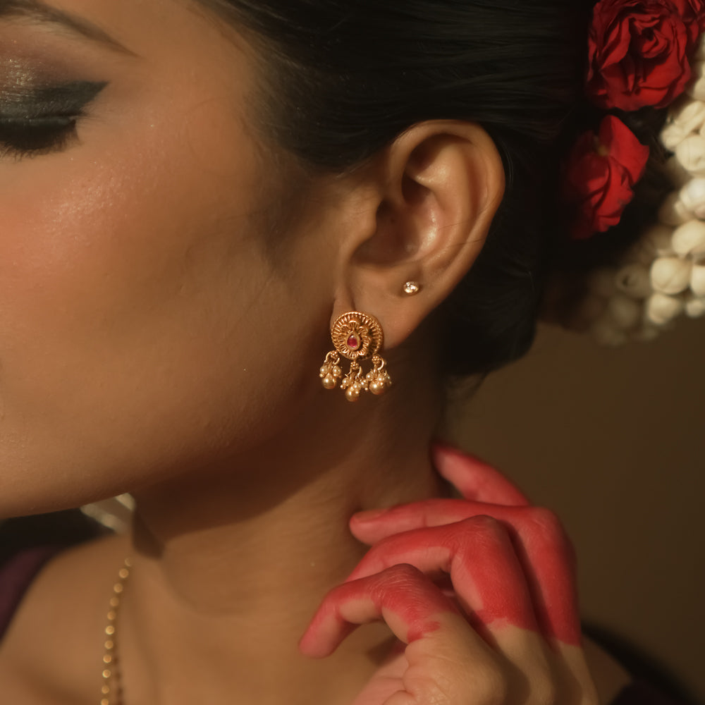 Gold-plated silver filigree earrings with a central crimson stone and tiny dangling beads.