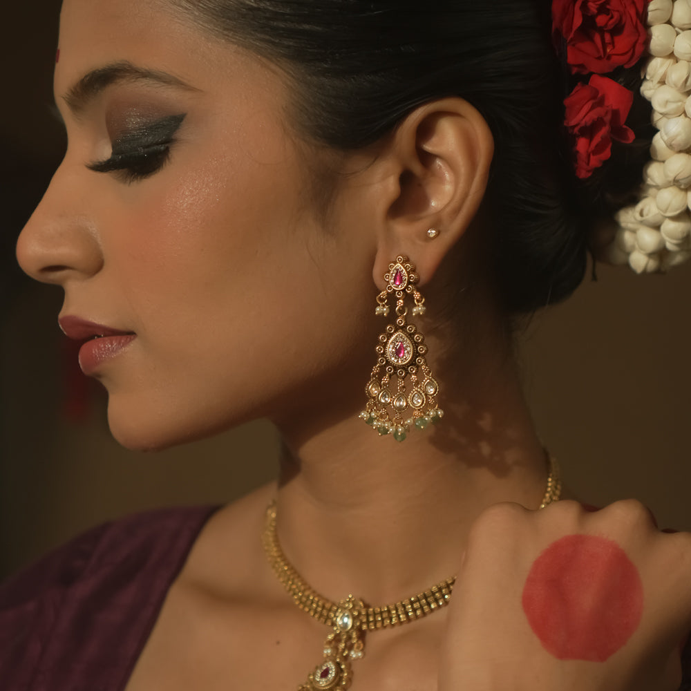 Tiered earrings with pink gemstones, clear Kundan stones, and emerald drops.