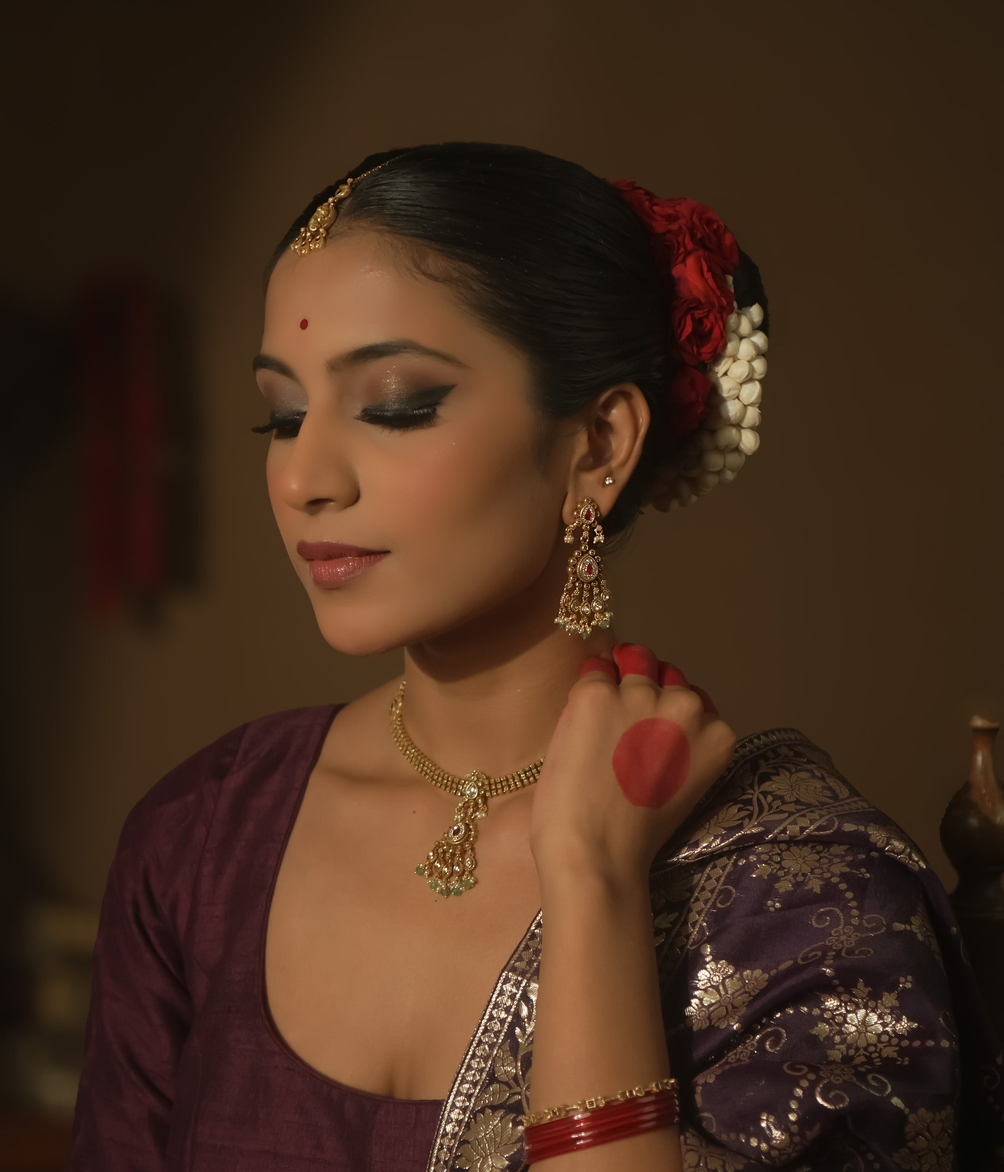 Tiered earrings with pink gemstones, clear Kundan stones, and emerald drops.