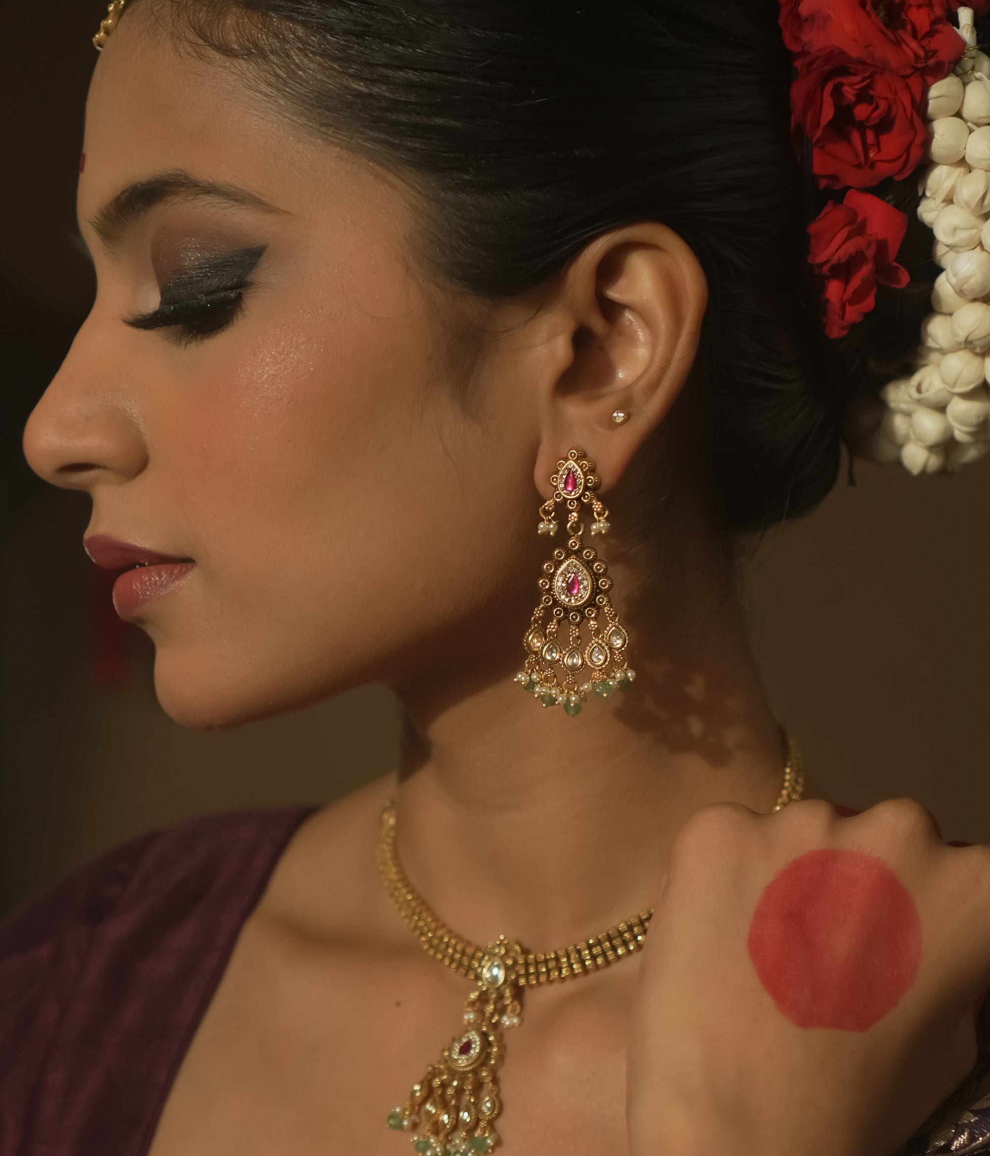 Tiered earrings with pink gemstones, clear Kundan stones, and emerald drops.