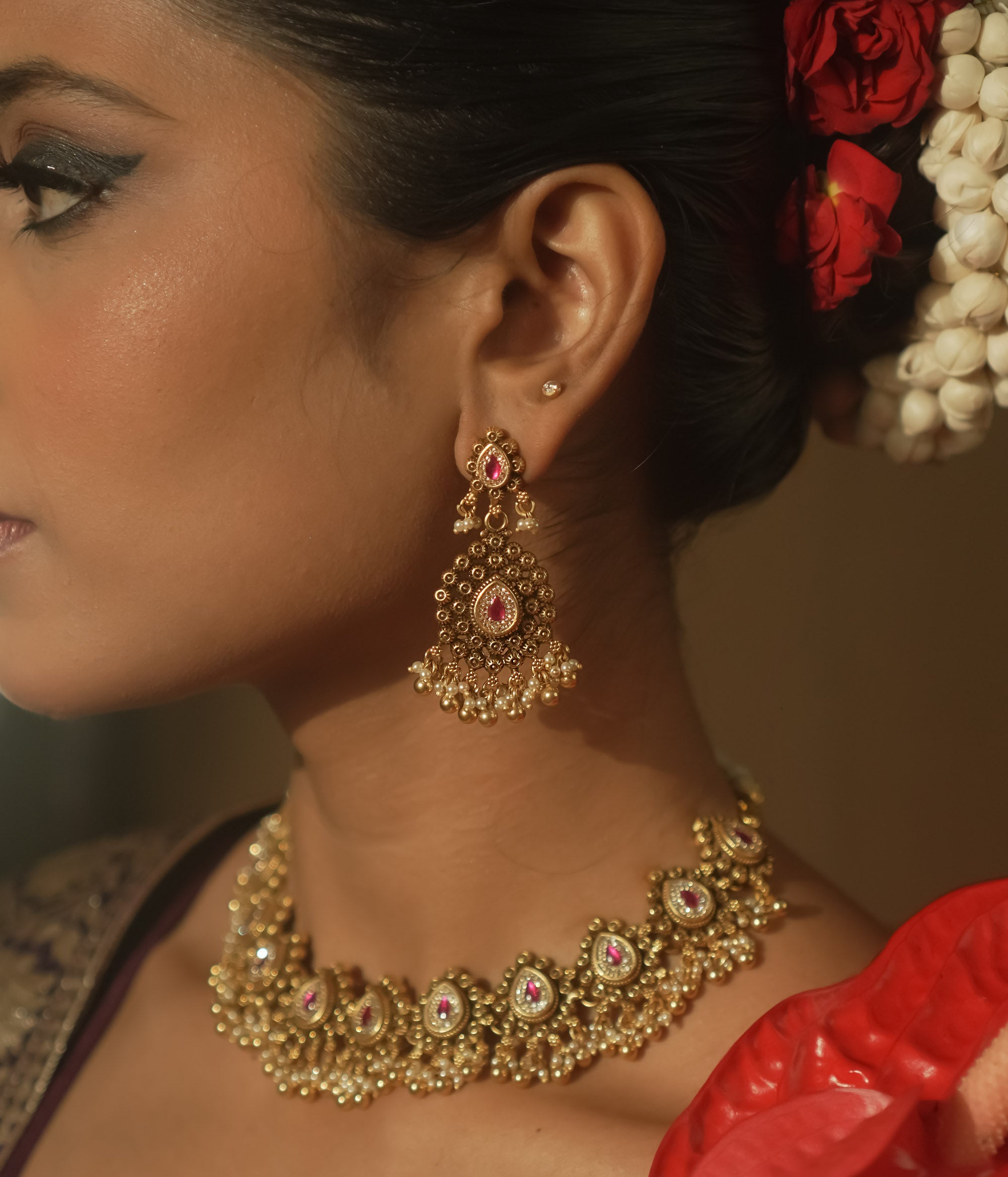 Gold-plated silver earrings with a teardrop shape, red gems, and cascading gold and pearl balls.