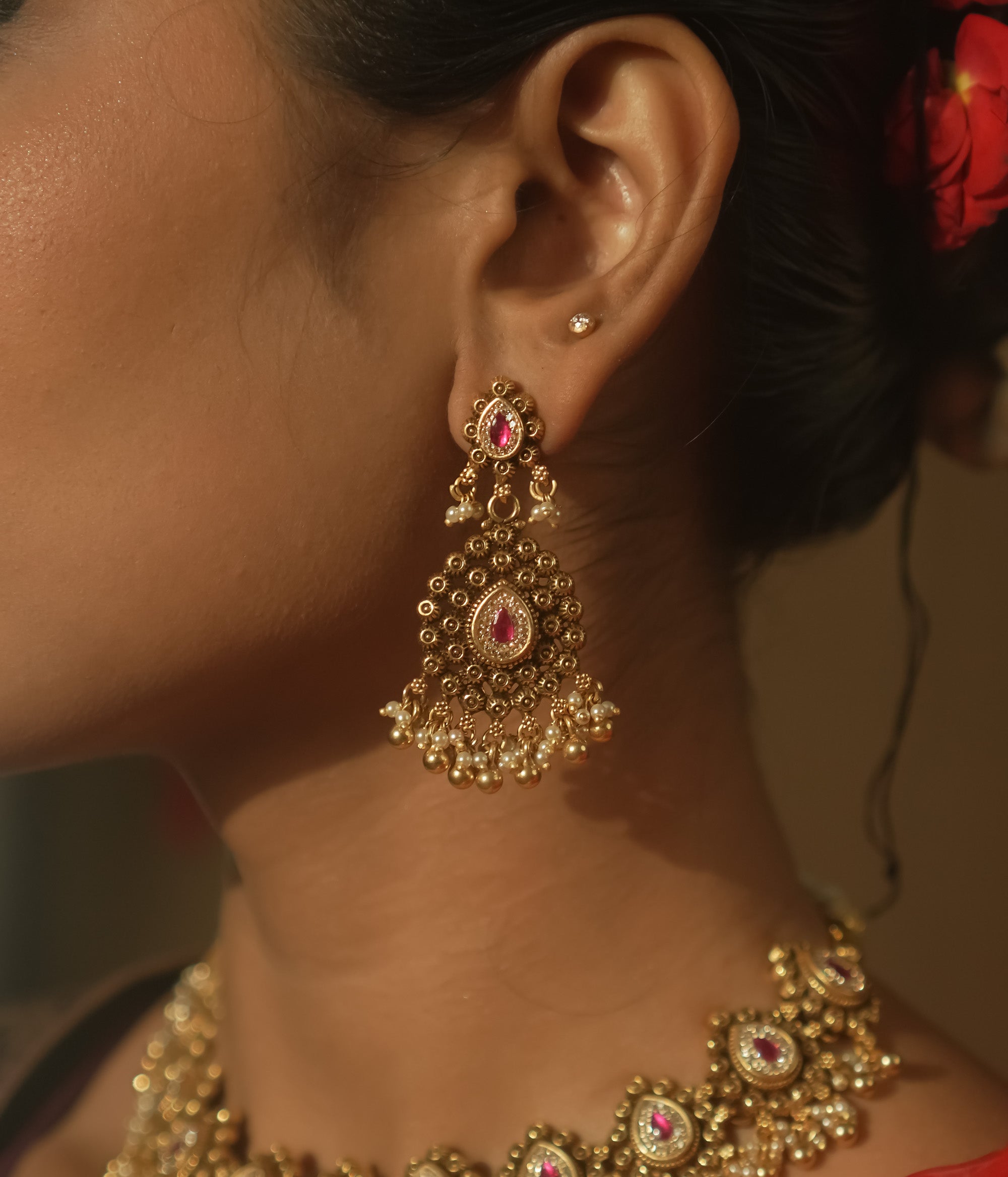 Gold-plated silver earrings with a teardrop shape, red gems, and cascading gold and pearl balls.