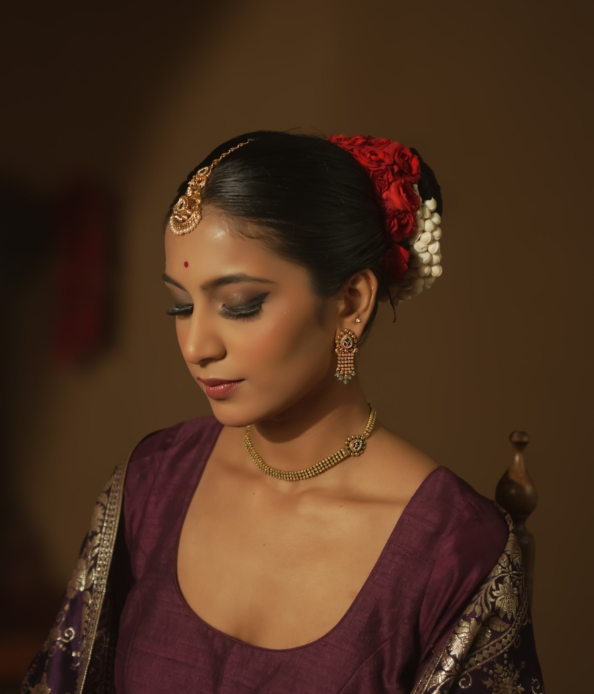 Gold earrings with teardrop charms, vibrant Kundan, and emerald fringes.