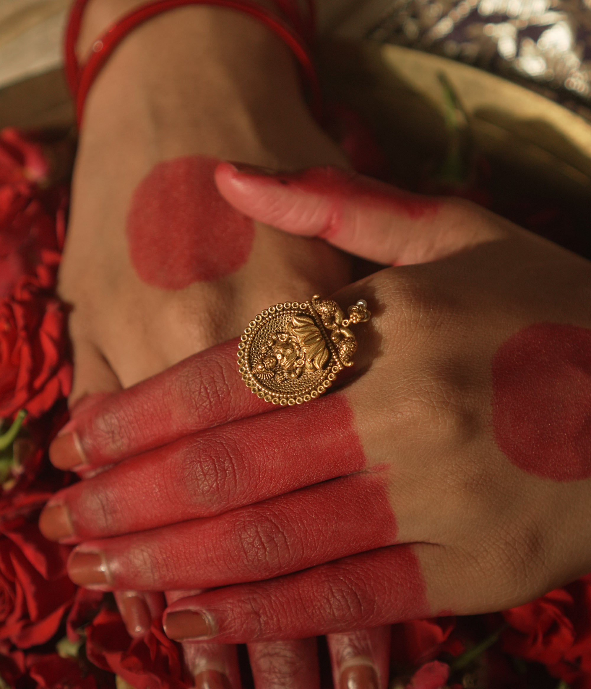 Gold ring with a central Lakshmi goddess motif and beaded edges.