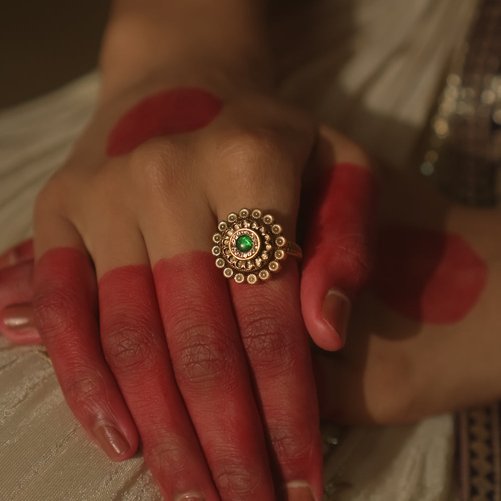 Gold-plated silver ring with a central green gem and a speckled dot pattern.
