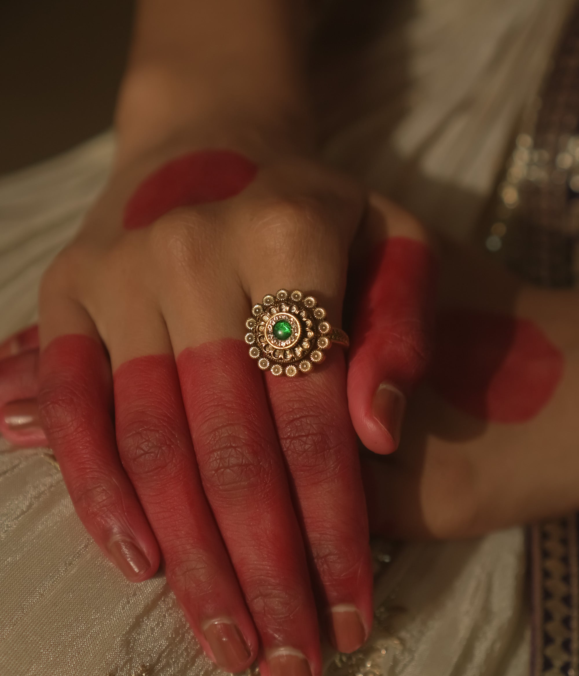 Gold-plated silver ring with a central green gem and a speckled dot pattern.
