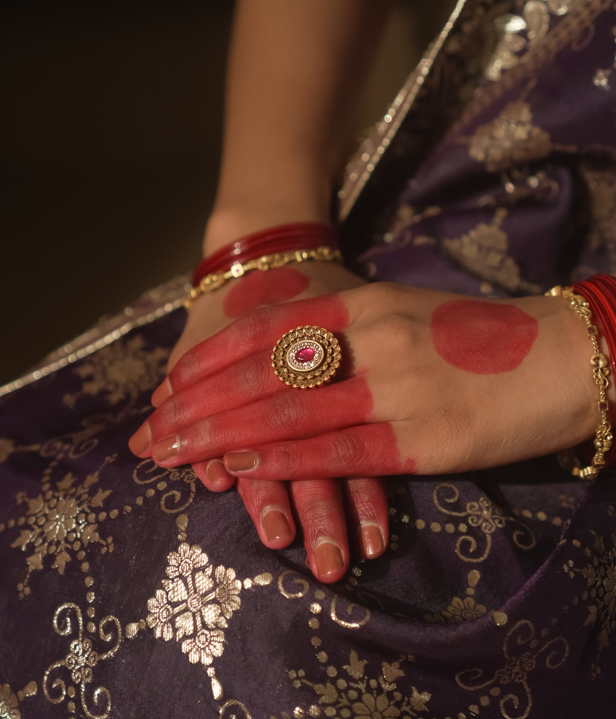 Gold ring with an antique design, tiny gems, and a central crimson jewel.