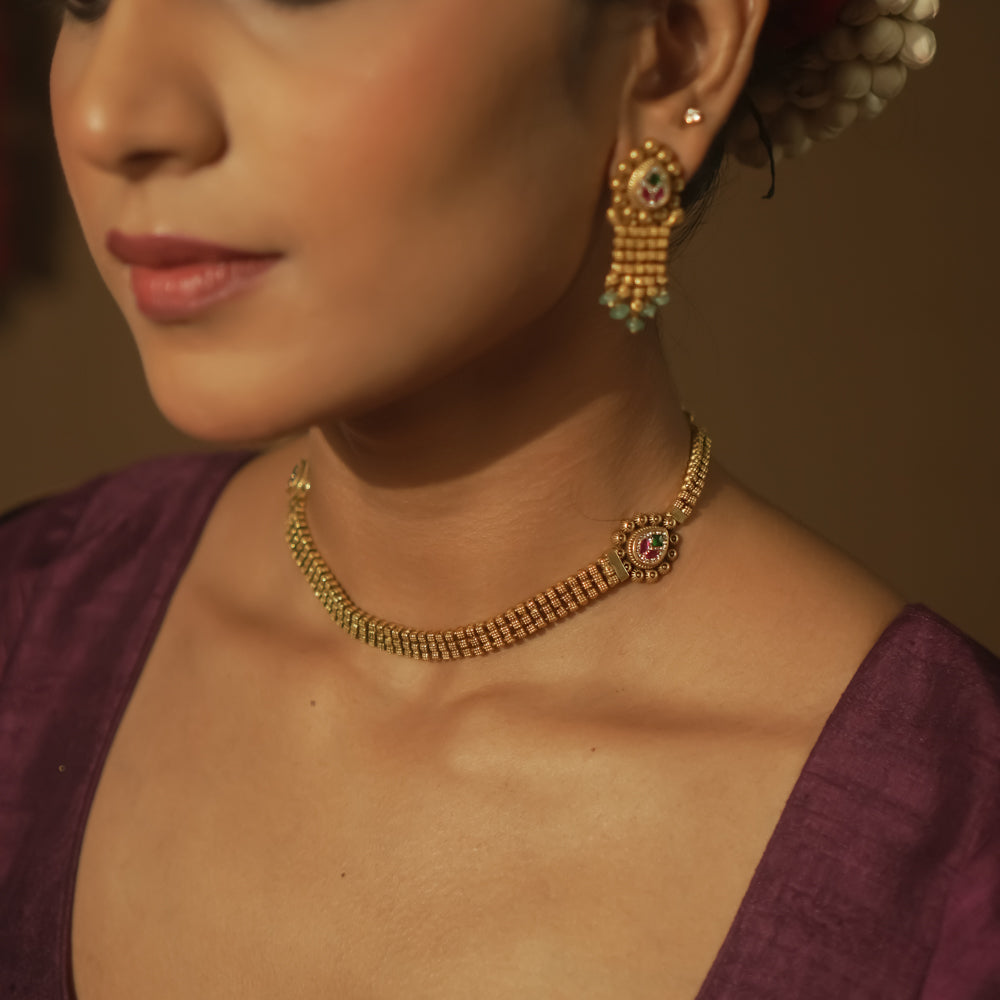 Gold mesh necklace with a gemstone pendant surrounded by tiny gold dots.